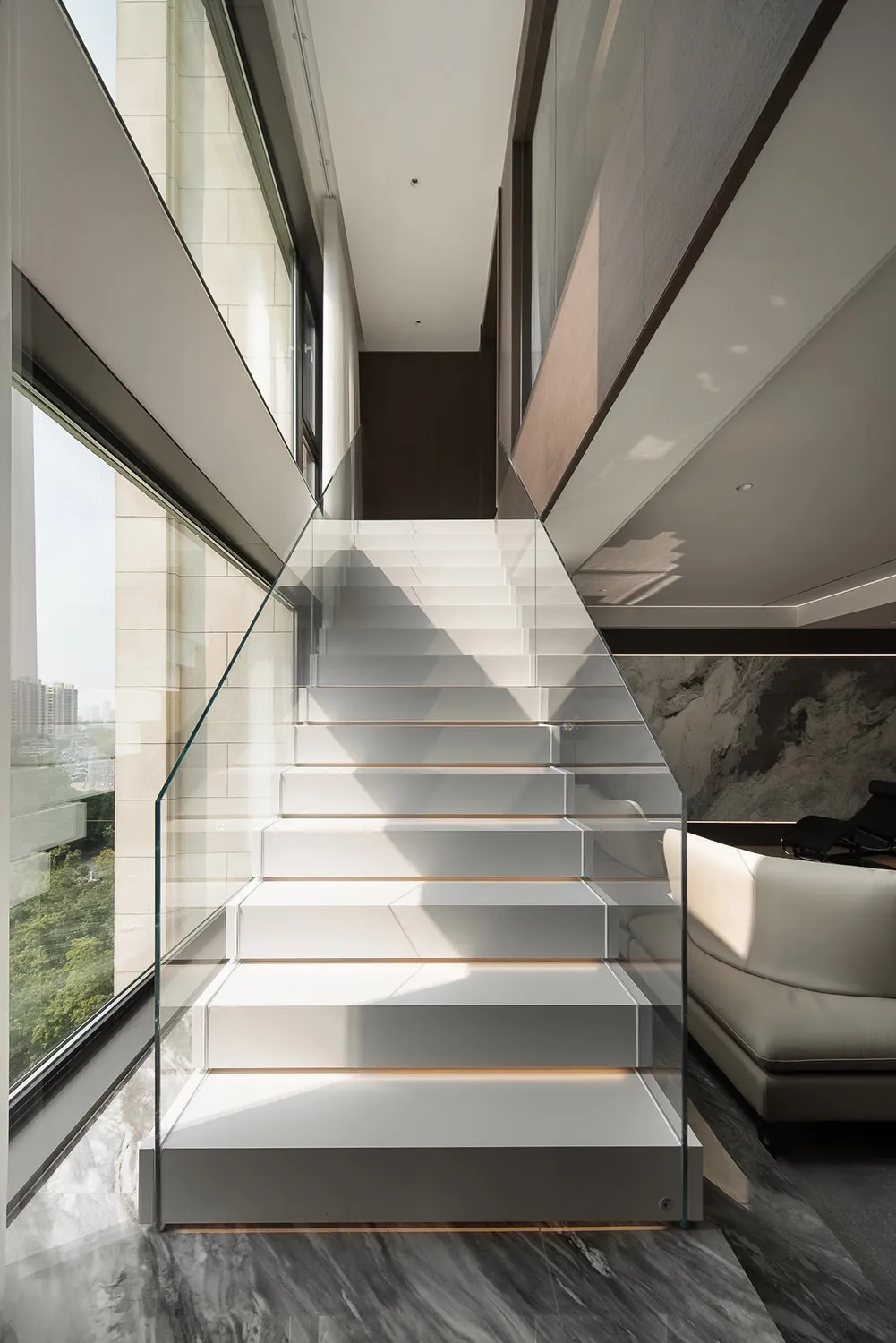 Modern staircase with glass railing and marble steps.