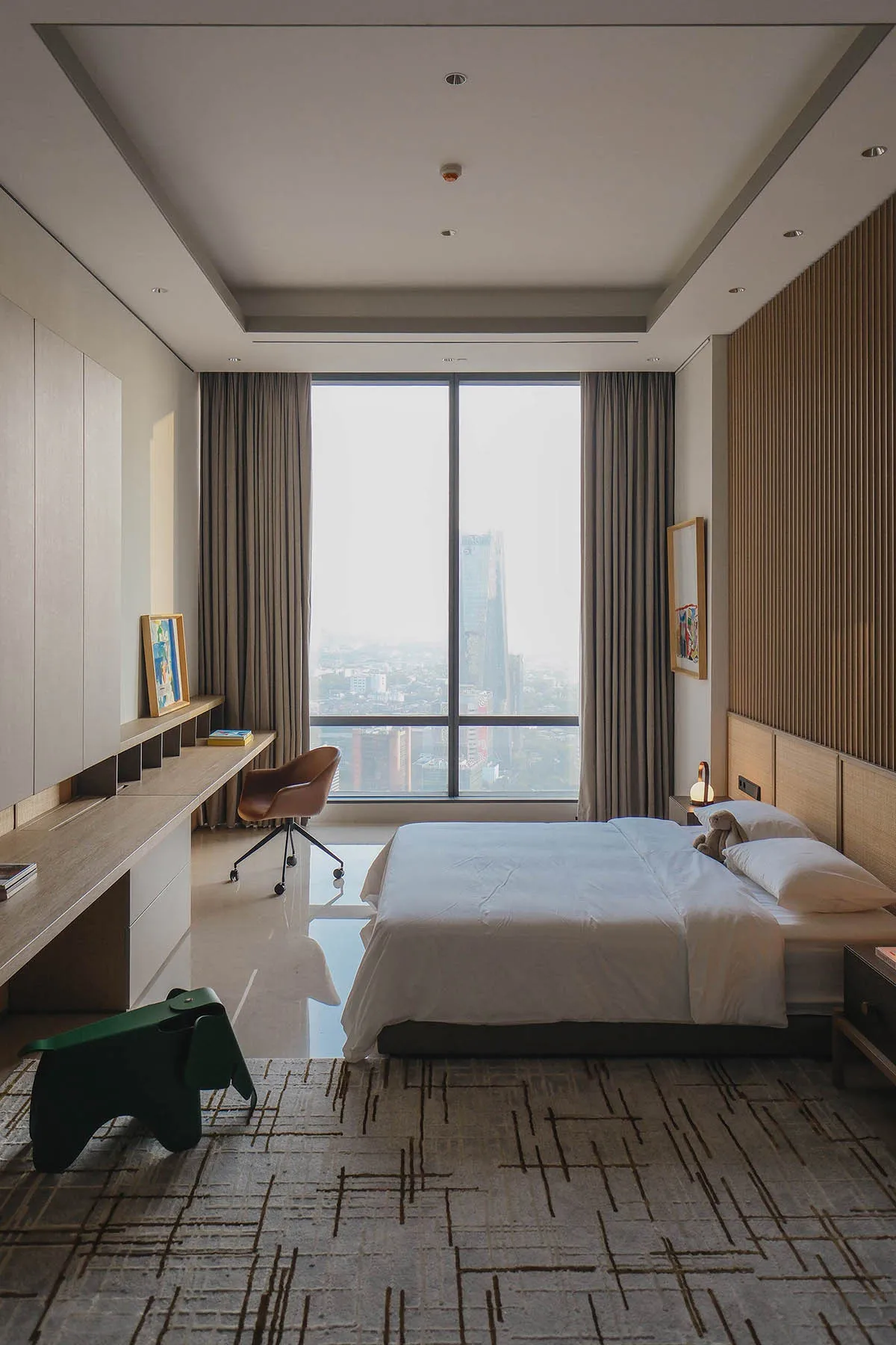 A minimalist bedroom with a grey bed and curtains, large window, and modern furniture.