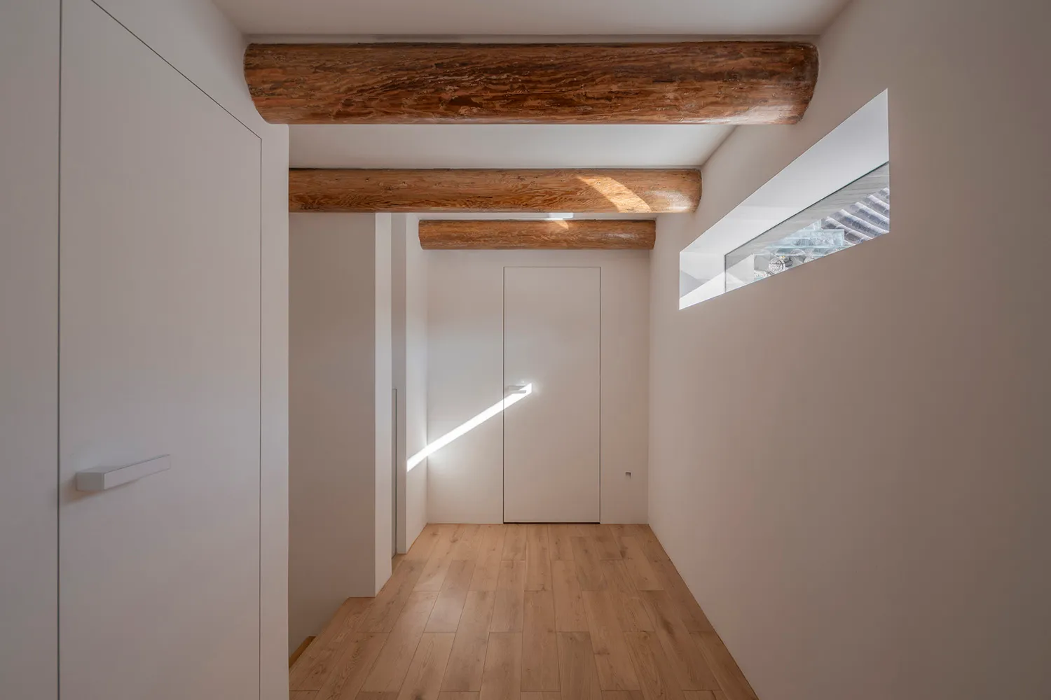 A minimalist interior design featuring wooden elements and a natural light source.