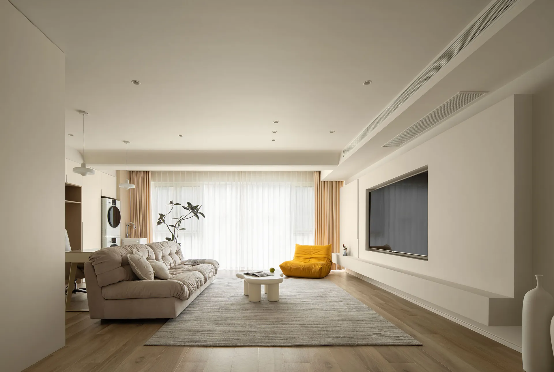 A modern living room with white furniture, wooden flooring, and a minimalist design