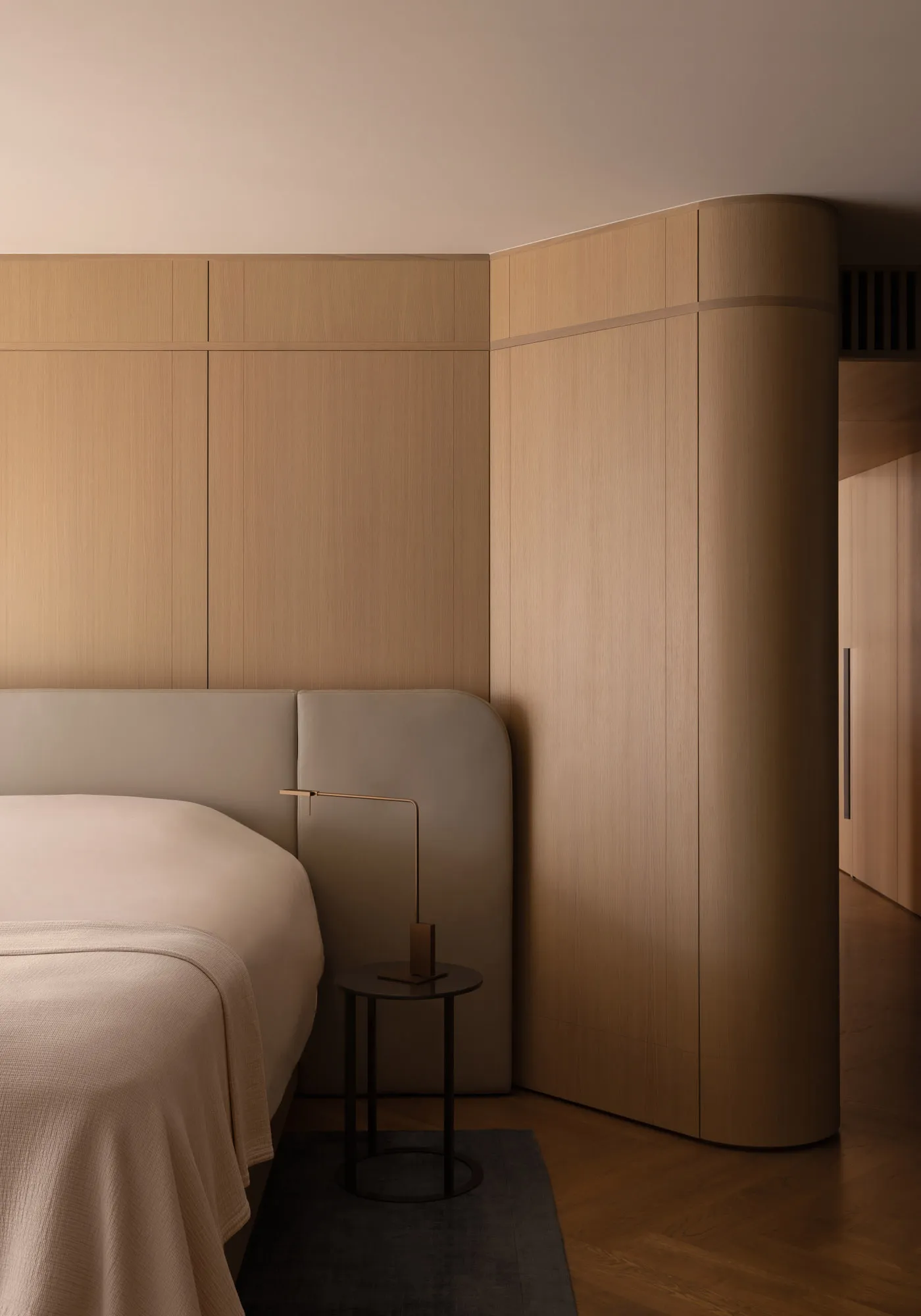 A minimalist bedroom with wooden walls and furniture, featuring a bed with a curved headboard and a small round side table wi