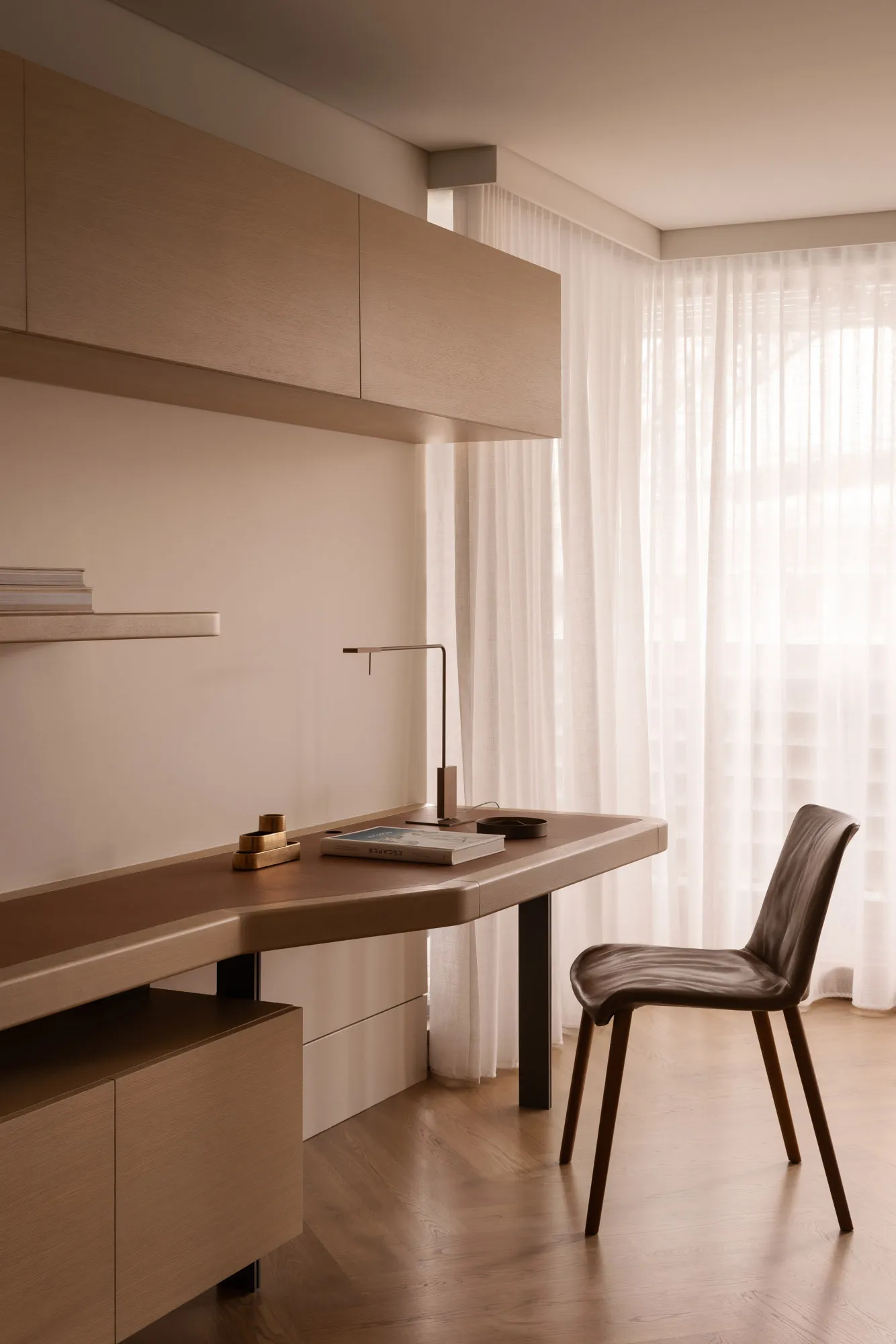 A modern minimalist study room with a wooden desk, chair, and bookshelf.