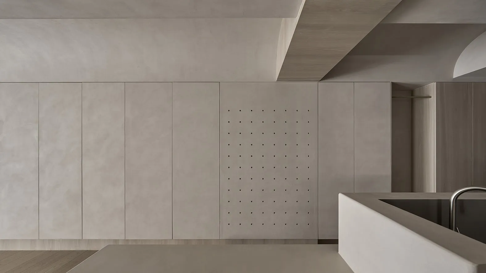A minimalist interior space featuring concrete wall panels with perforated holes.