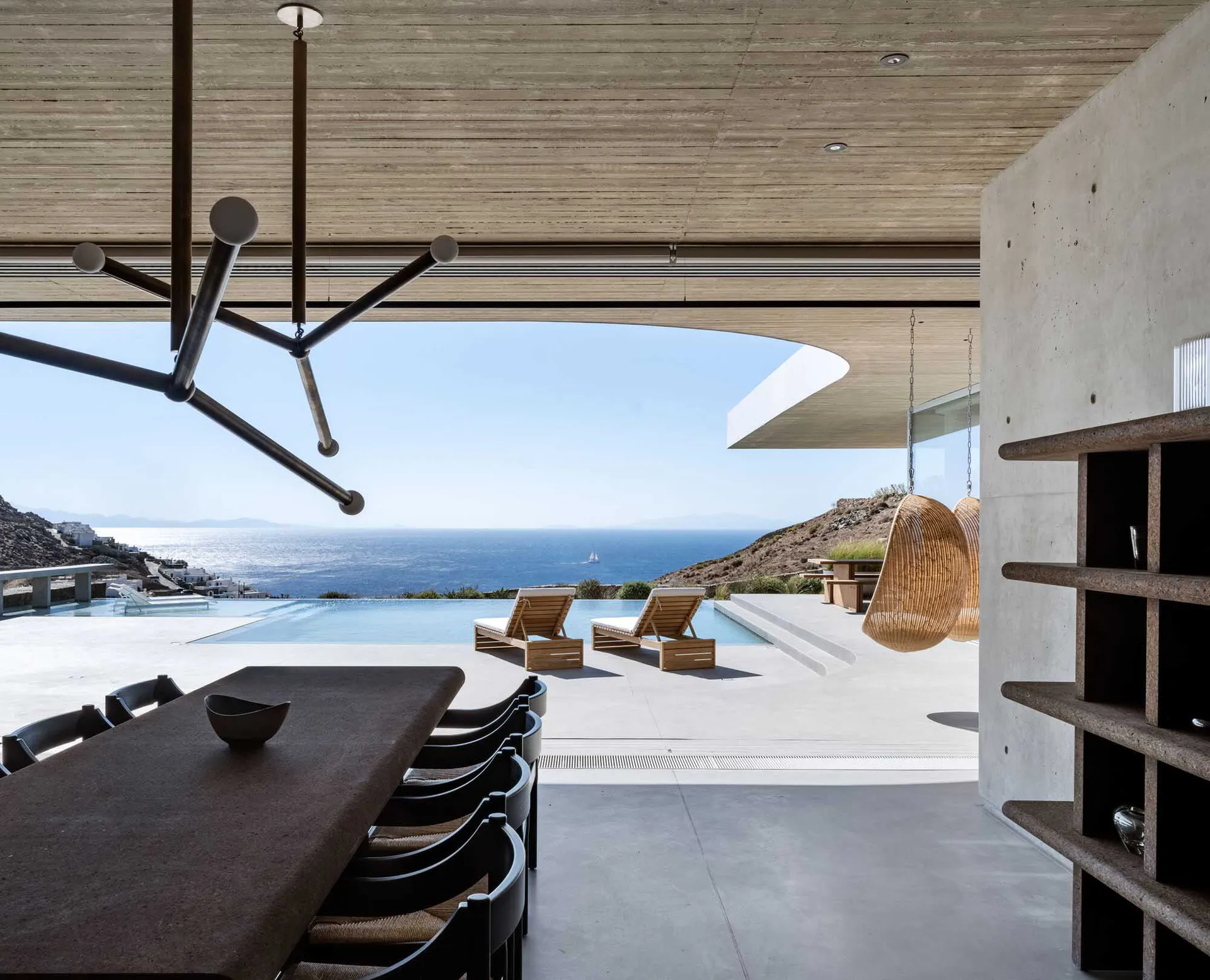 Concrete patio with lounge chairs, infinity pool, and scenic ocean view