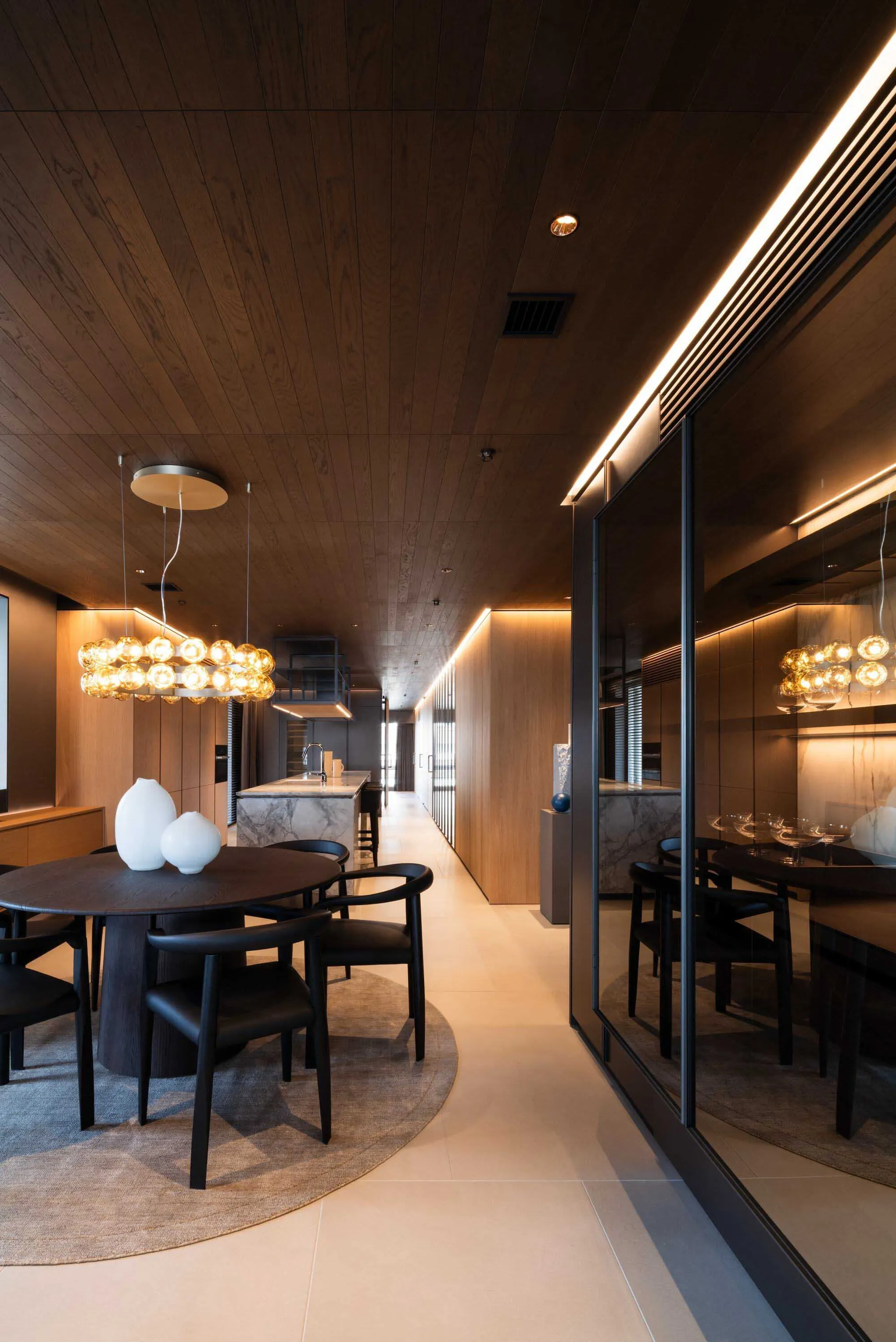 Modern dining room featuring wooden panels, round table, and pendant lights.