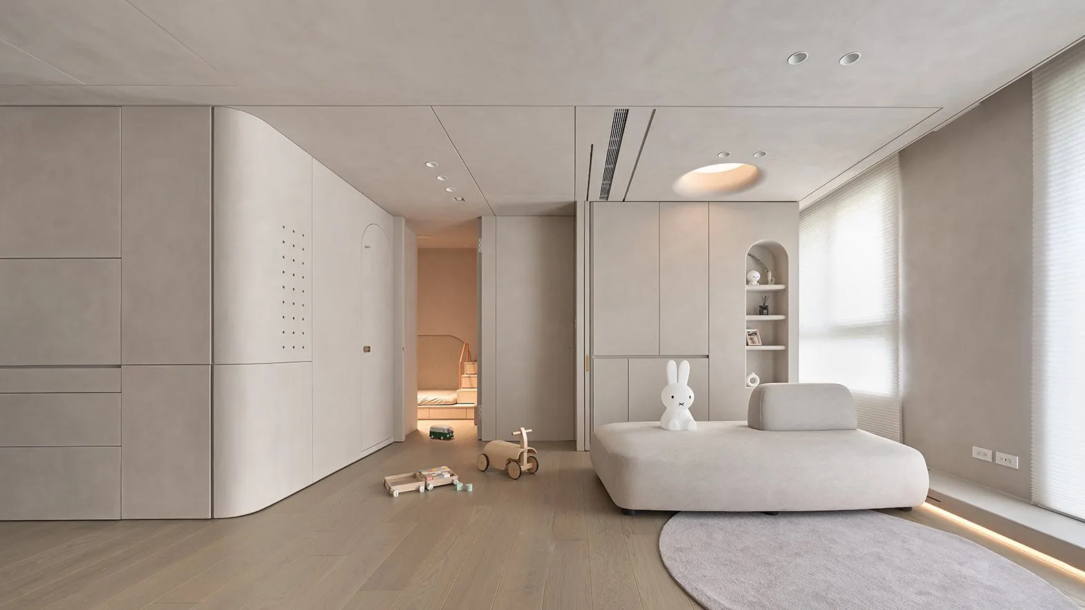 A minimalist bedroom with a fabric seating area, white cabinetry, and modern design elements.