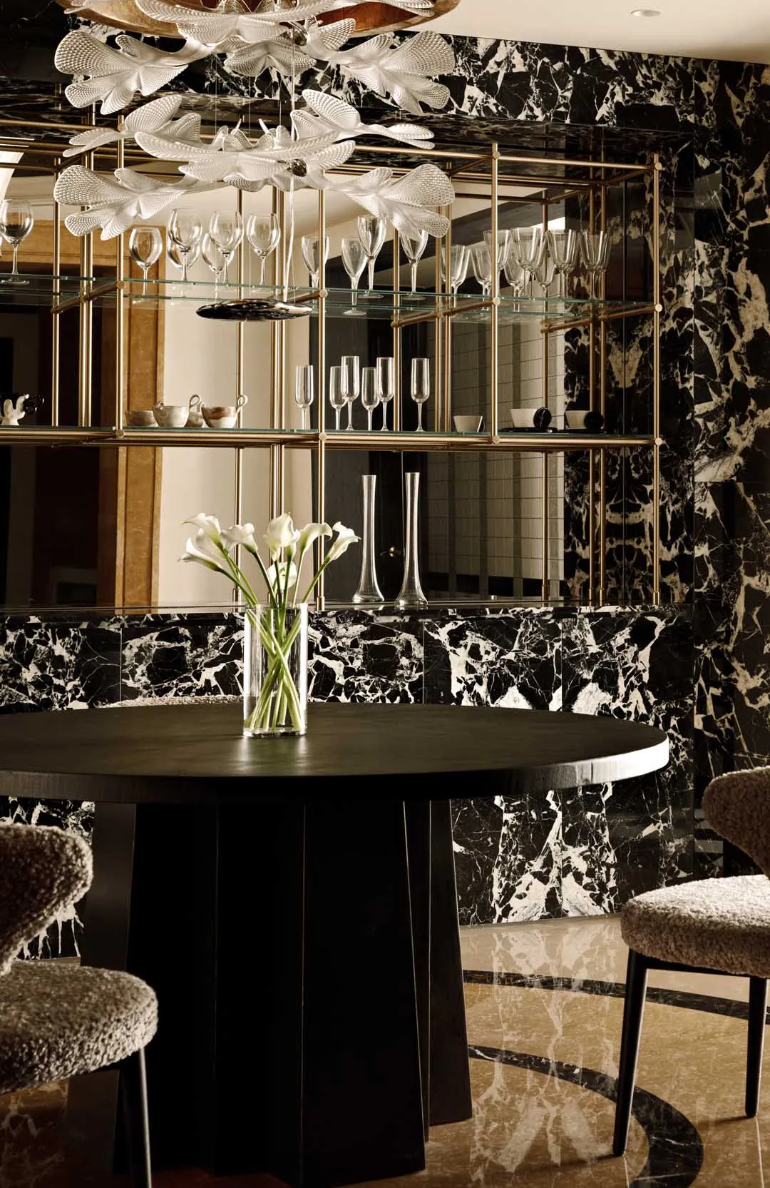 Modern dining room featuring marble walls, glass shelves, and a wooden dining table.