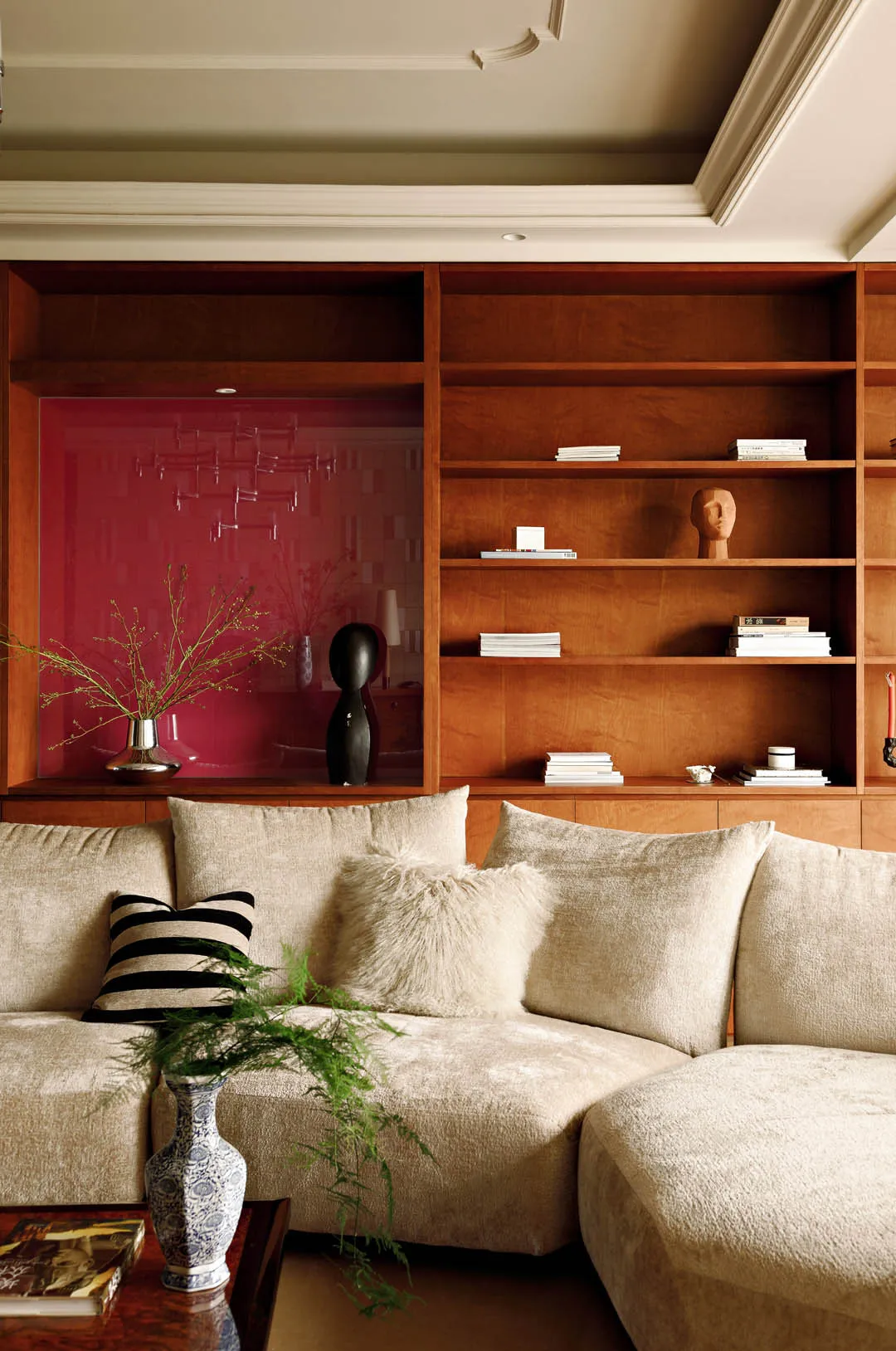 A modern living room featuring a comfortable couch adorned with plush cushions and throw pillows, alongside a bookshelf fille