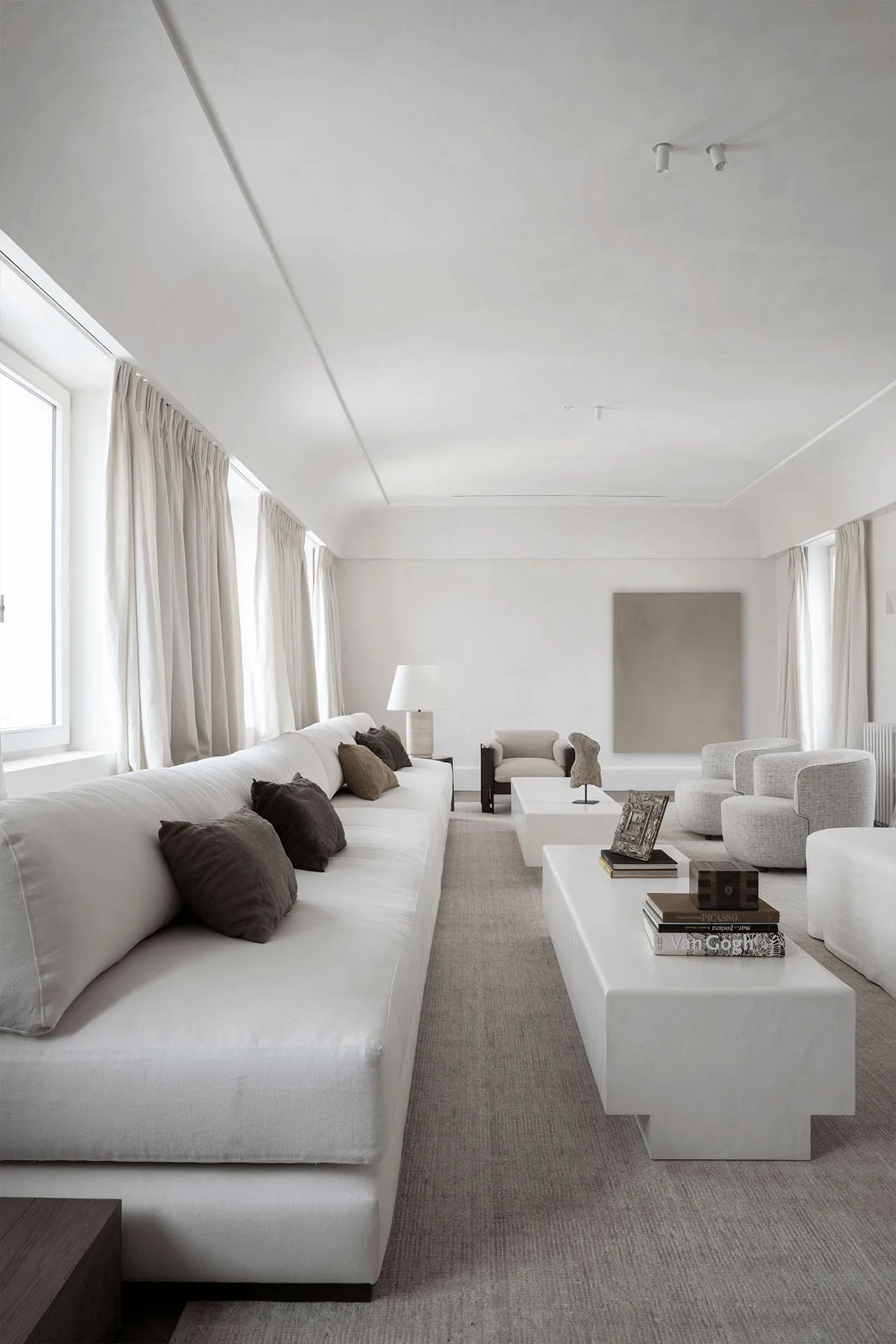 A modern living room featuring a monochromatic color scheme with fabric furniture and minimalist decor.