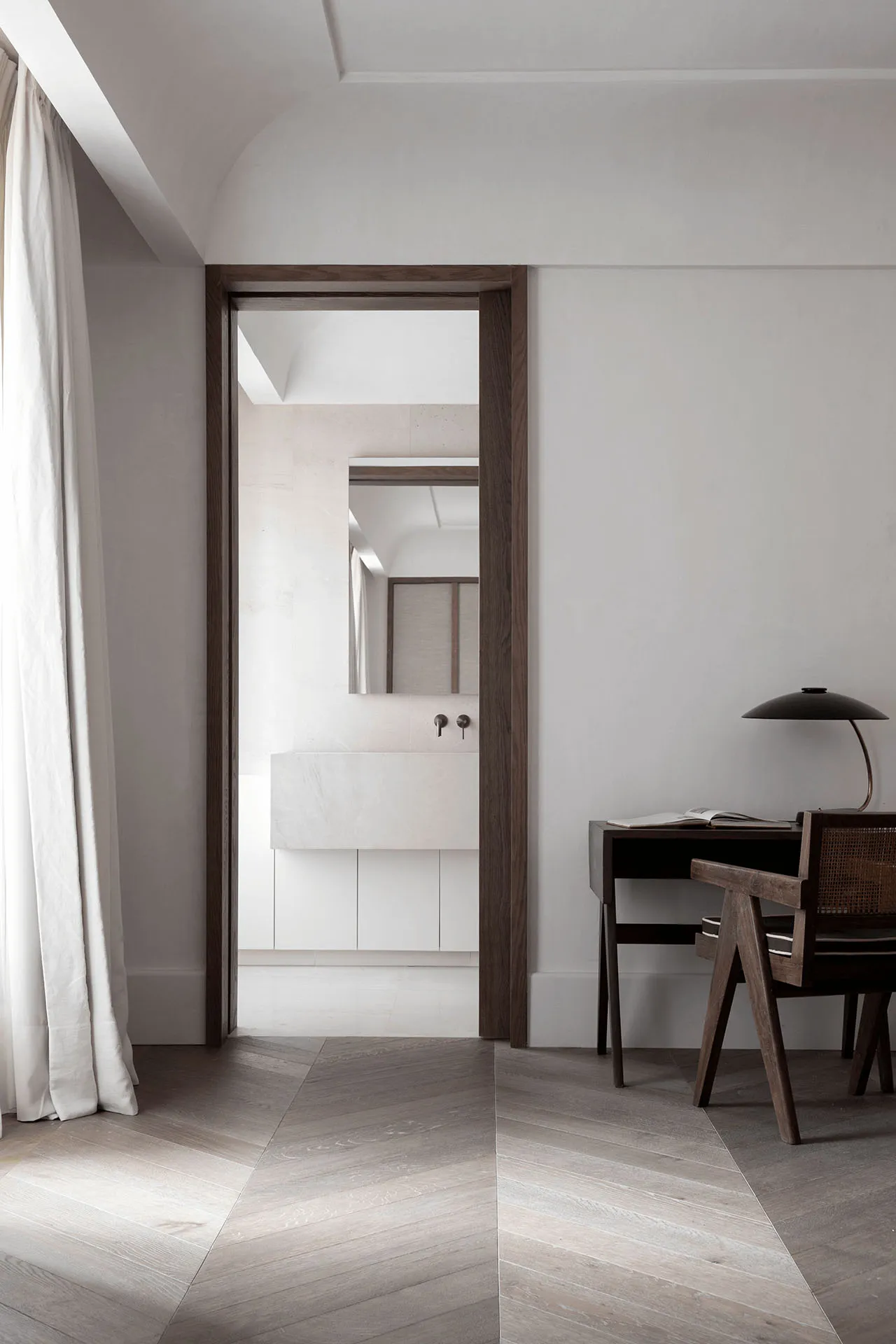 A minimalist bedroom with a terrazzo floor and light wooden furniture, featuring a bathroom with a terrazzo vanity sink and m