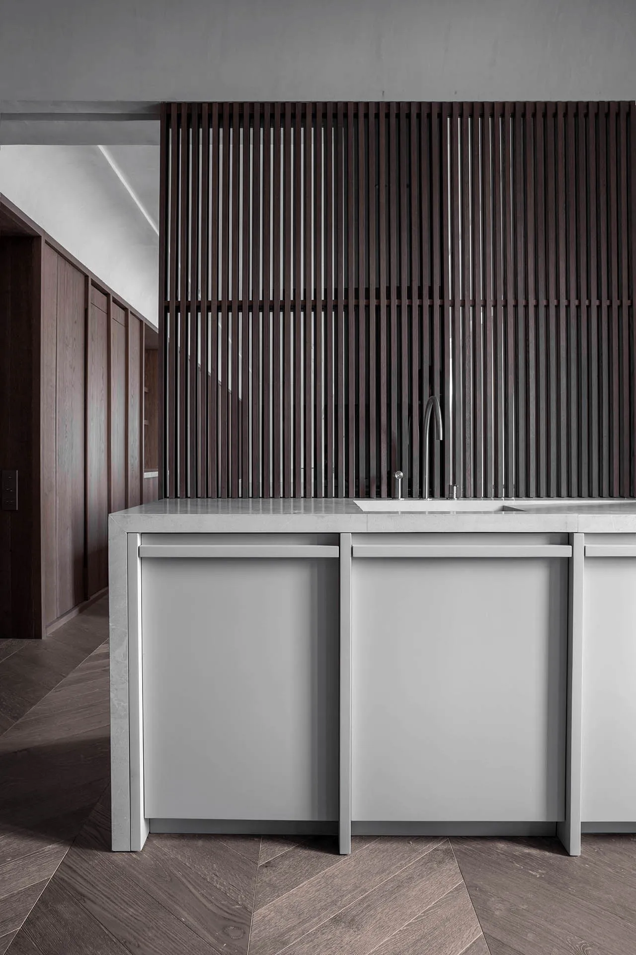 A modern minimalist kitchen with wood elements, featuring a sink and cabinets.