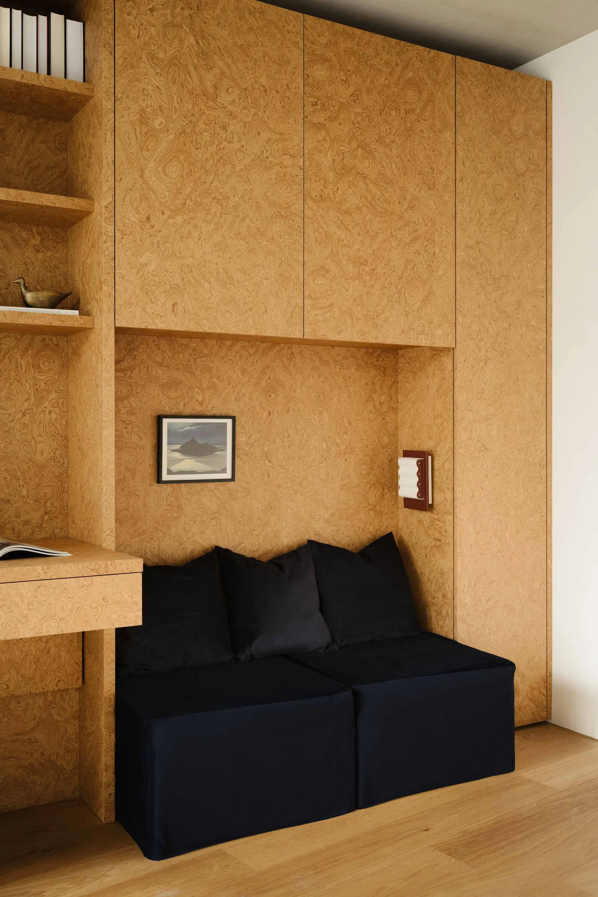 Modern, minimalist residential interior with black cushions and wooden walls and shelves.