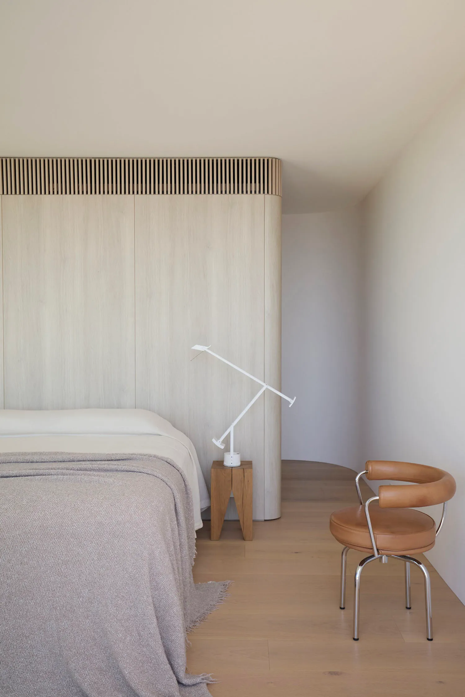 A modern bedroom featuring wooden elements, minimalistic design, and a comfortable bed.