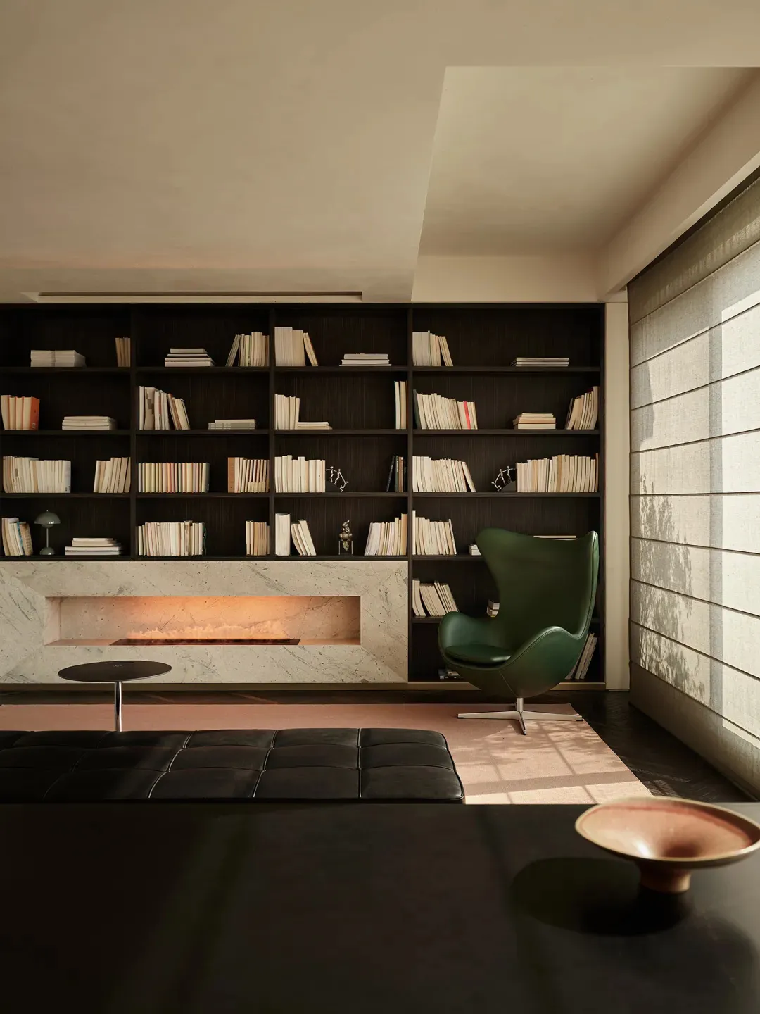 A modern living room featuring a marble library and a green armchair.