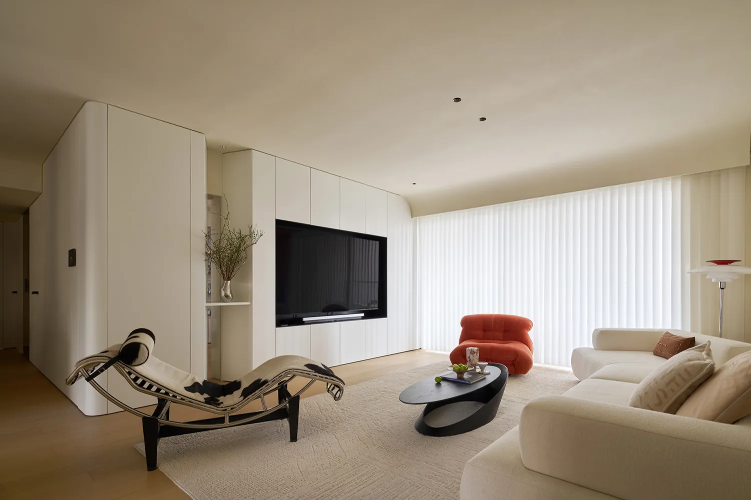 Modern living room with white furniture, minimalistic design, and a large window with roller blinds.