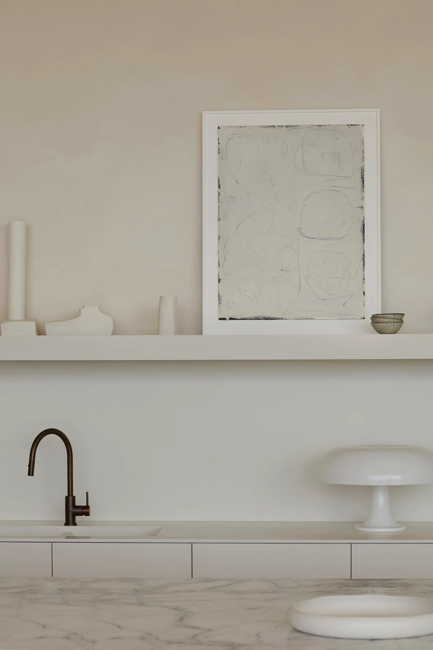 Modern kitchen with marble countertops, minimalist design style, and white floating shelves.