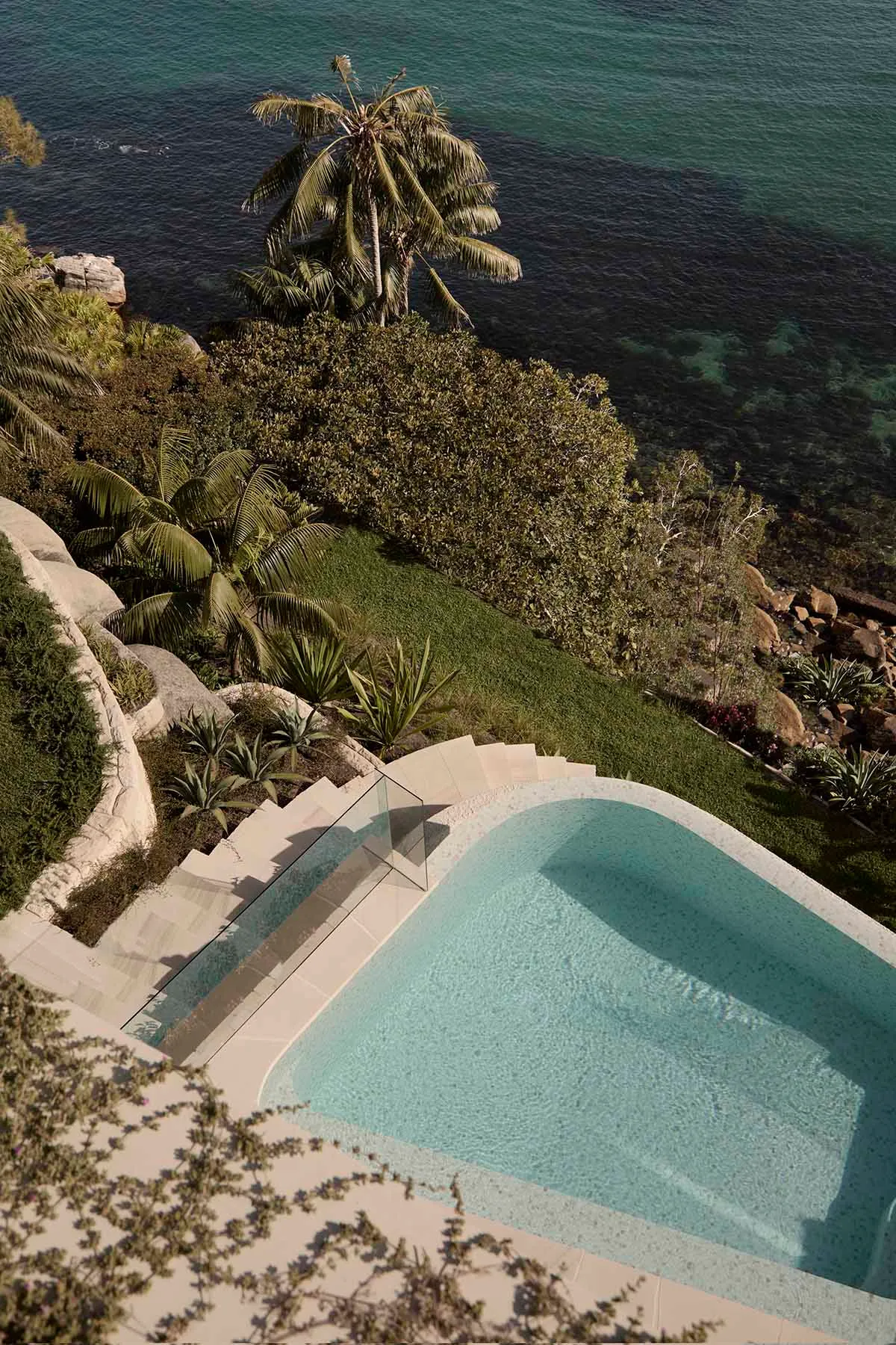 A modern pool with a terrazzo finish overlooks the ocean.