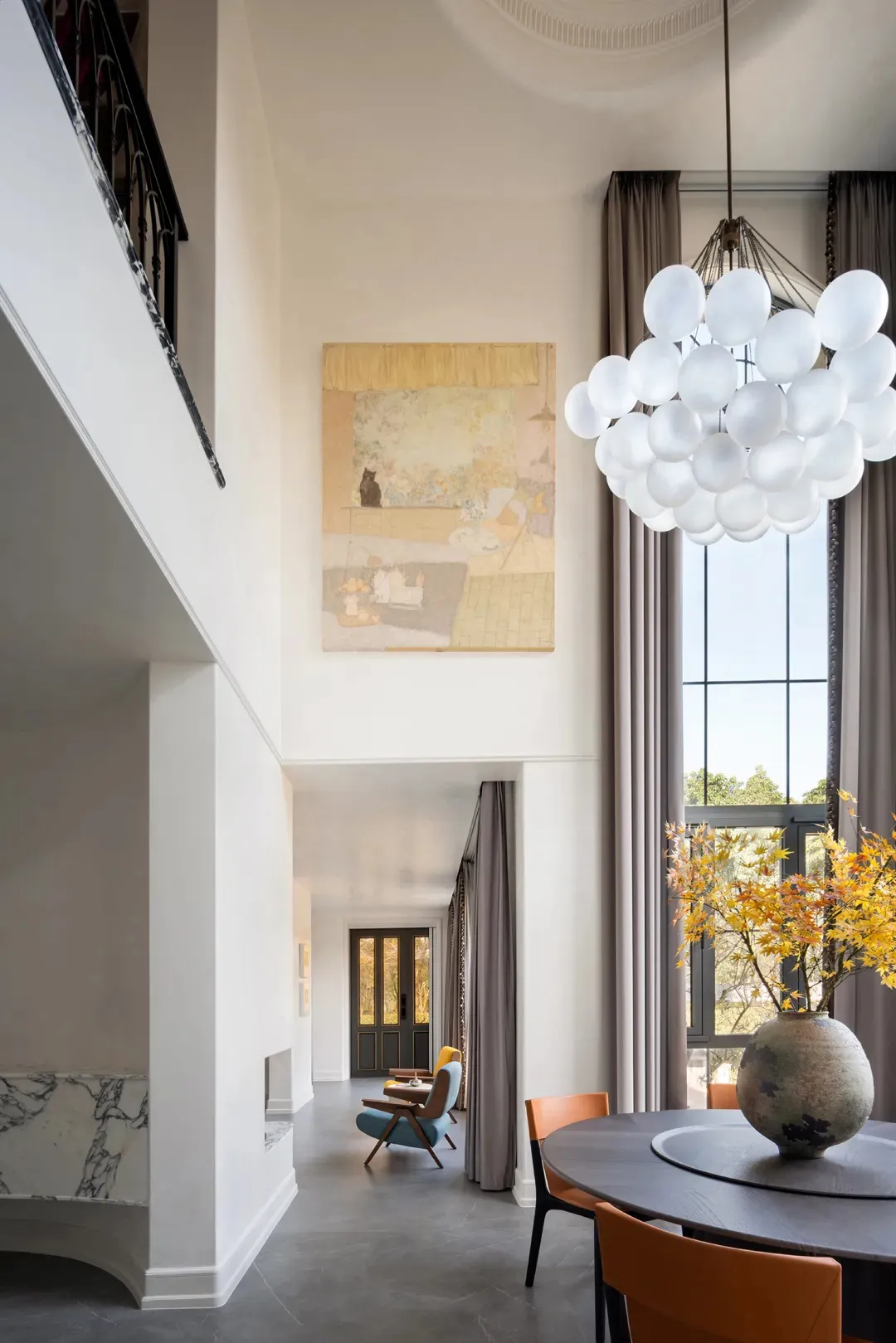 An elegant dining room with modern elements, featuring a marble table, acrylic chairs, and a concrete floor.