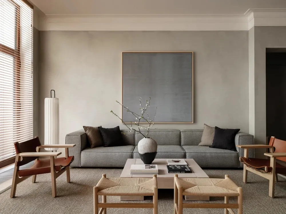 Minimalist living room featuring a concrete floor, fabric sofa, wooden chairs, and a concrete coffee table.