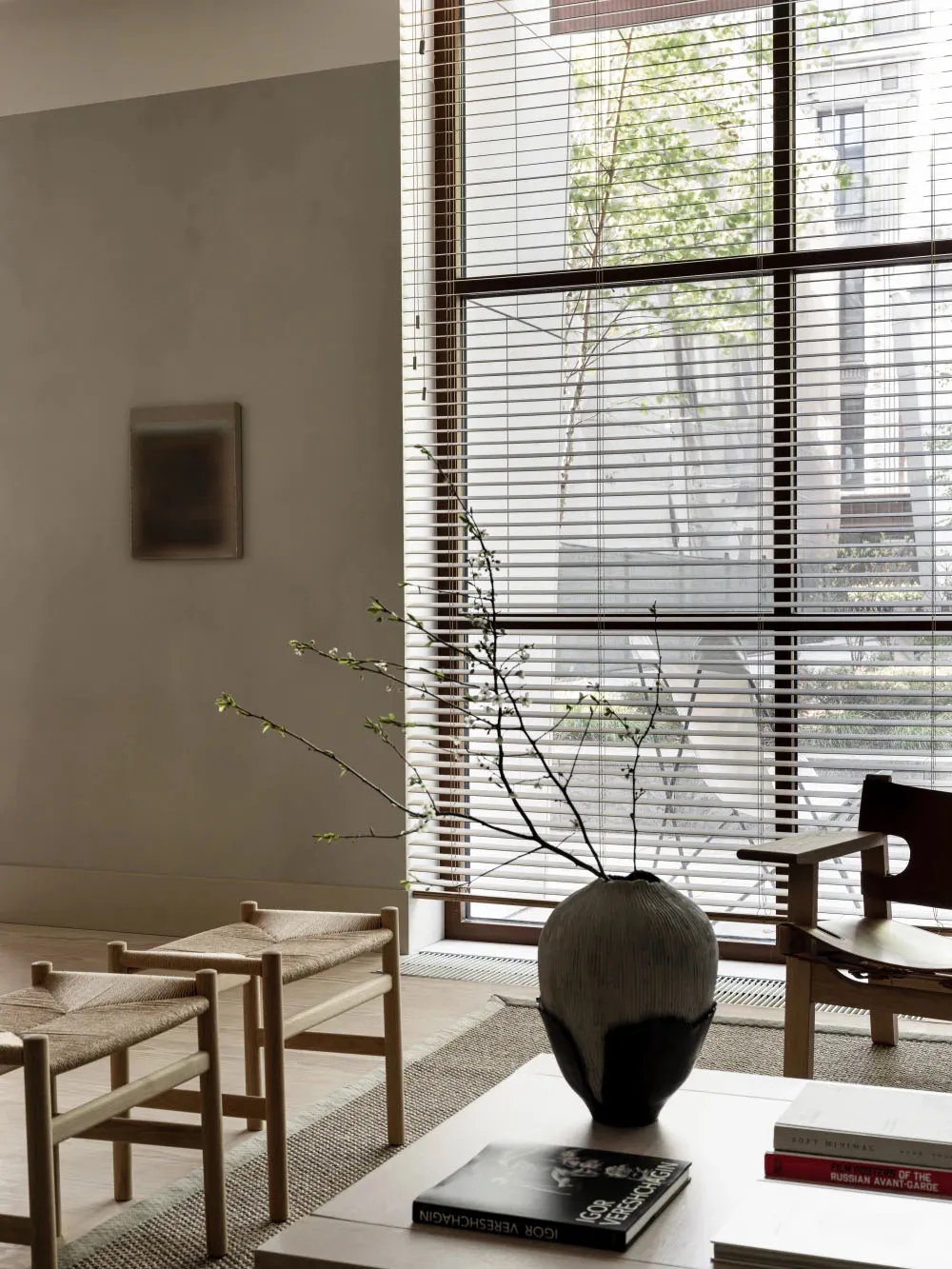 A minimalist living room featuring wooden furniture, glass windows, and metallic accents.
