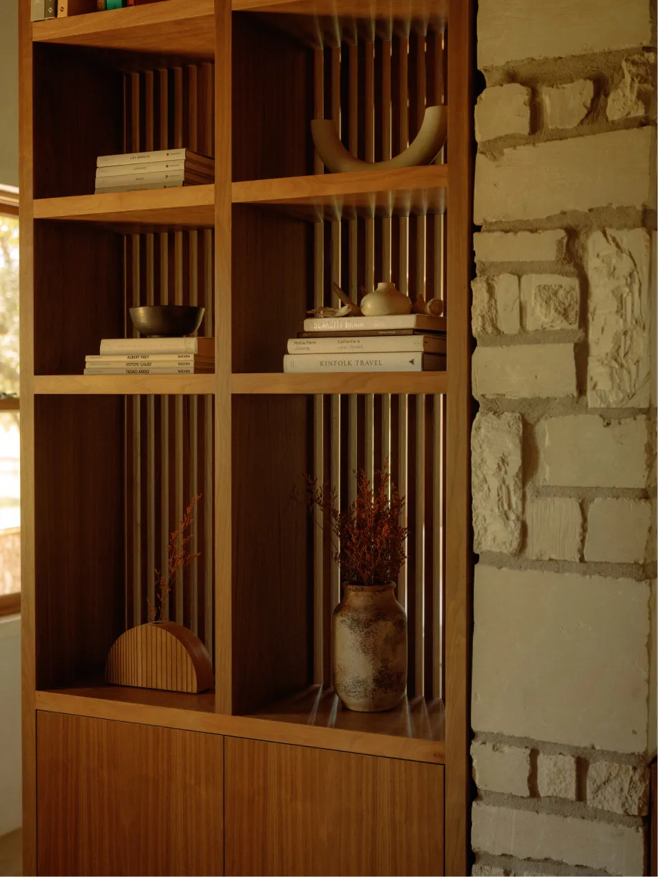 A modern wooden bookshelf with books and decorative items.