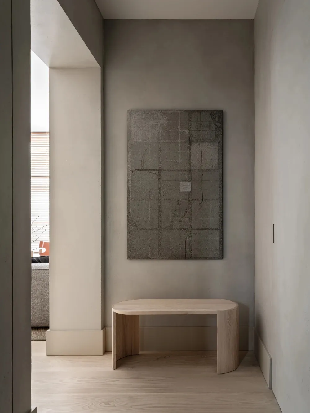 A minimalist entryway featuring a wood and concrete side table and abstract artwork.