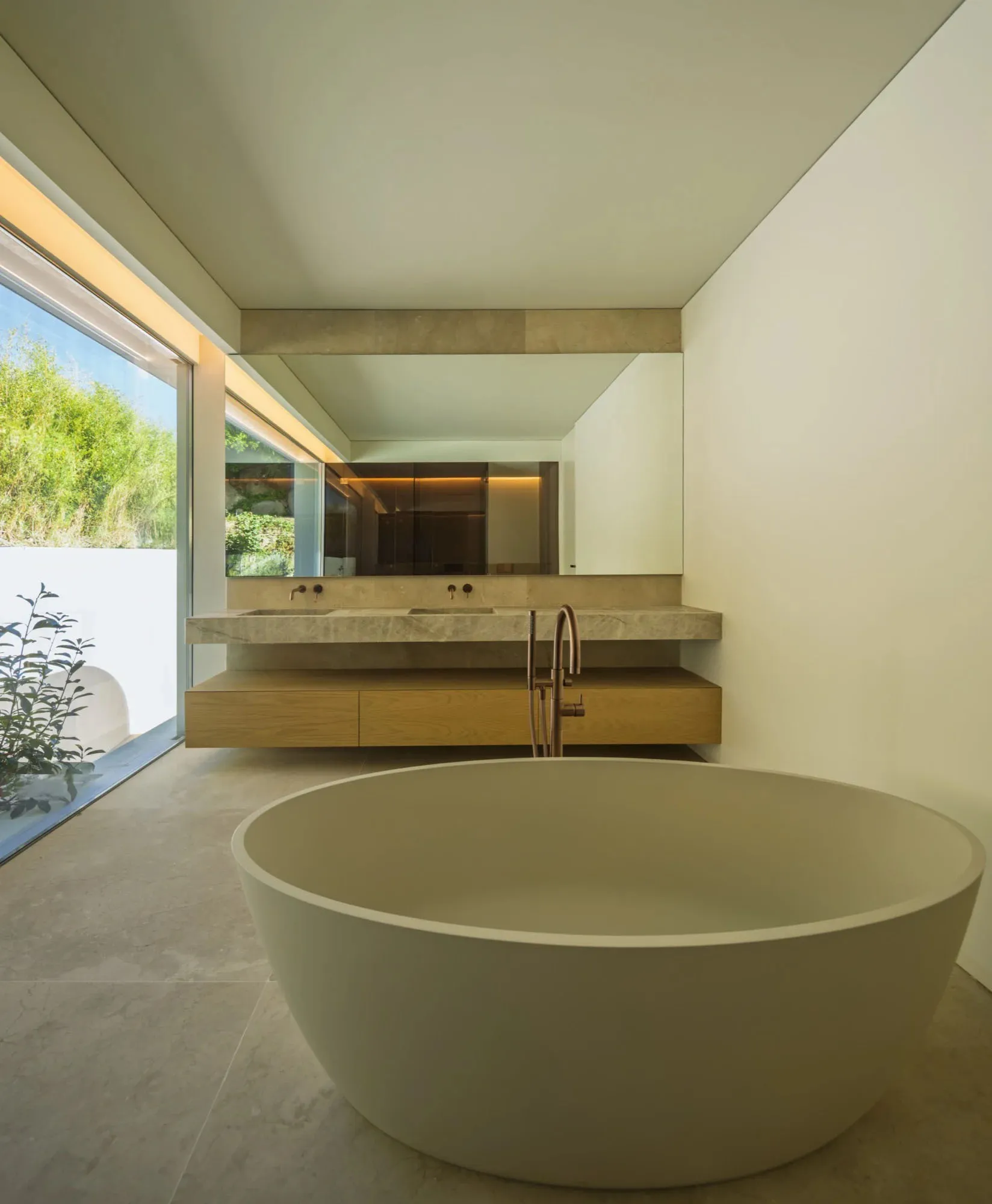 Contemporary minimalist bathroom featuring a freestanding tub, floating vanity, and large window