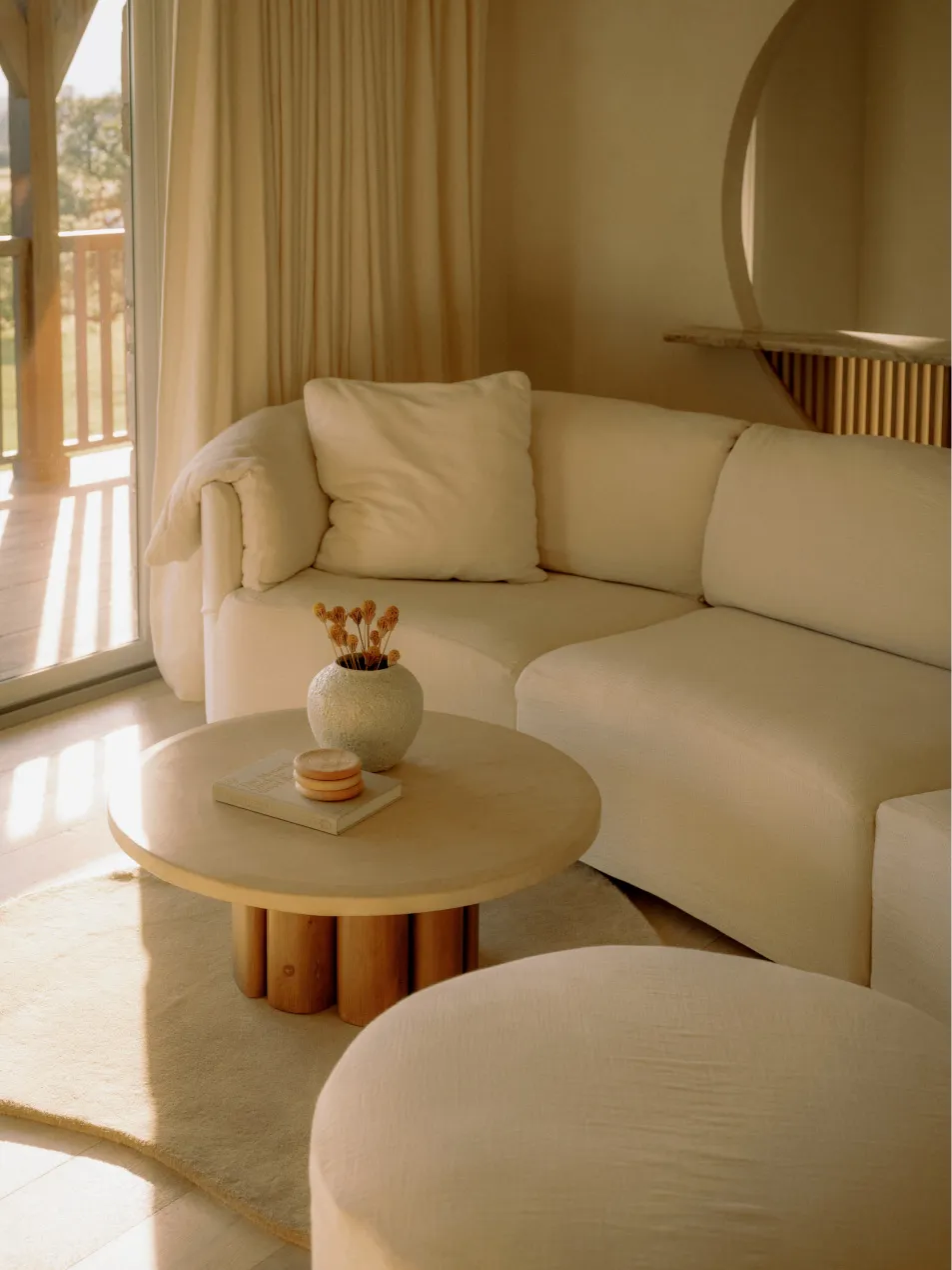 A modern, white fabric sofa in a contemporary living room setting with a round table and natural light.