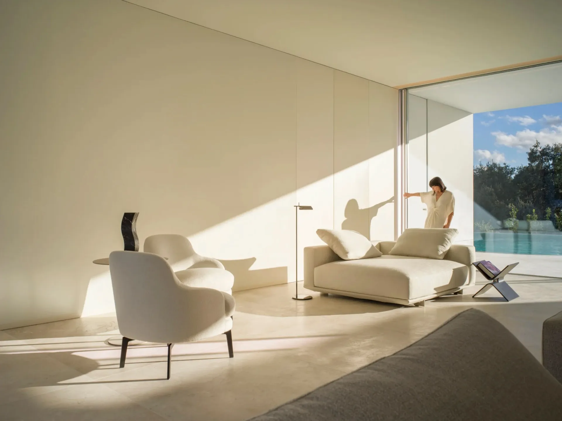 White minimalist living room with modern furniture and floor-to-ceiling windows.