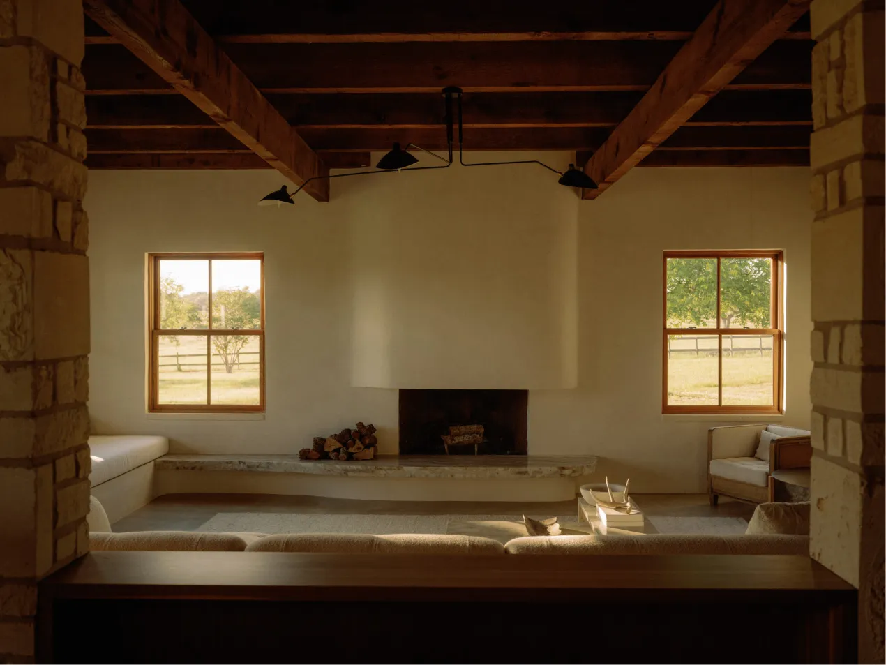 A minimalist living room with stone walls and a large window overlooking a green landscape.