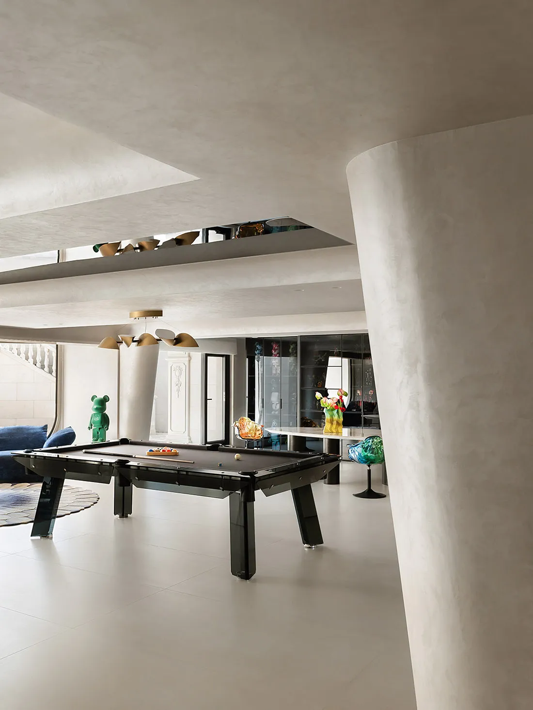 Modern living room with concrete walls and floor, featuring a sleek, black pool table and contemporary furnishings.