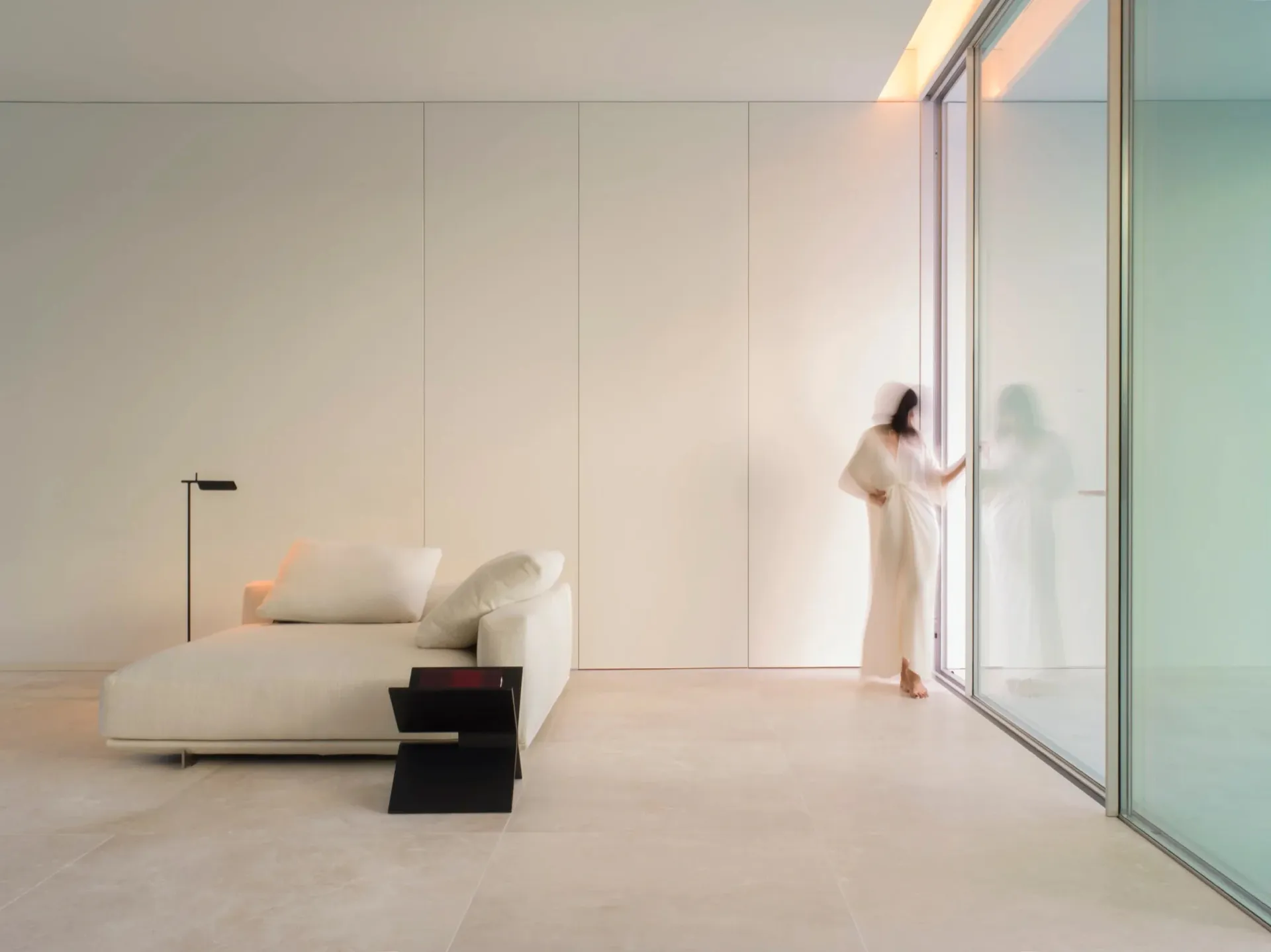 A minimalist living room featuring glass walls and a sleek, contemporary sofa.