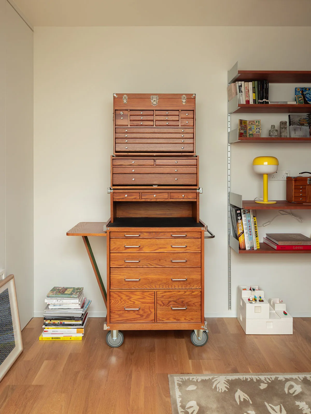 A wooden tool cart with multiple drawers and shelves.