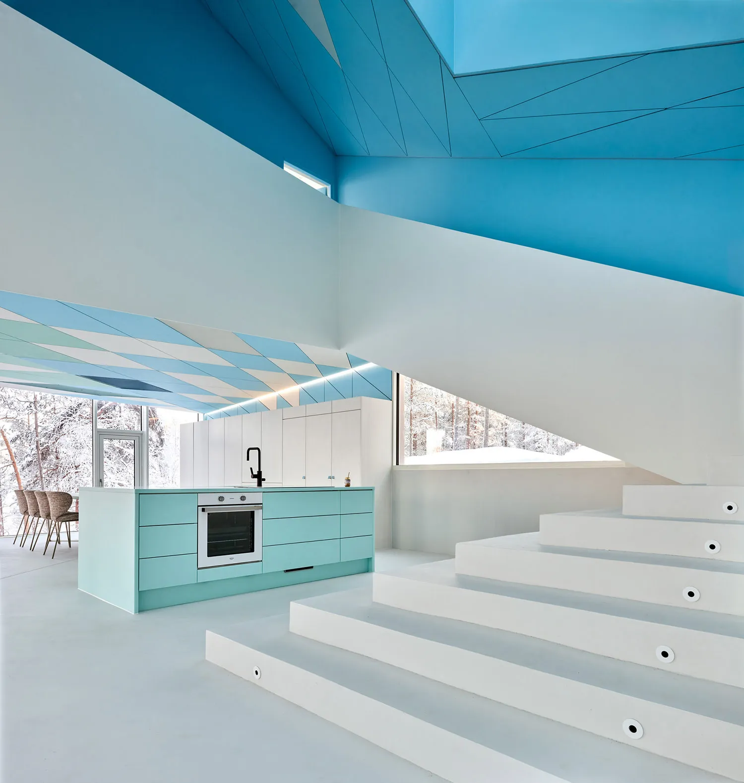A modern kitchen with a concrete staircase and white walls.