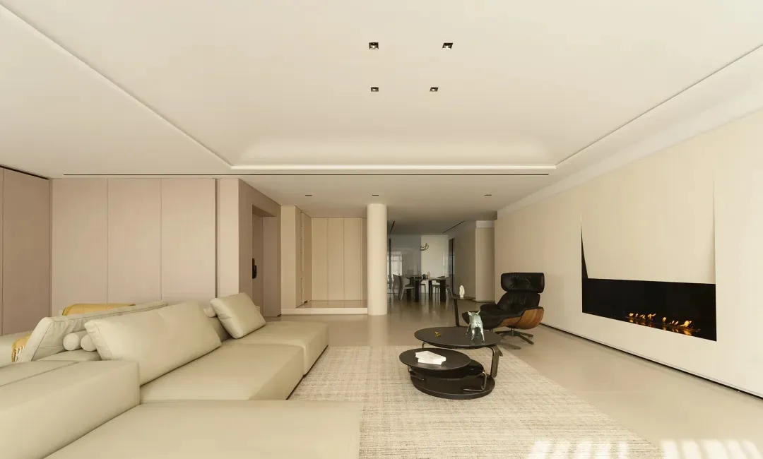 A modern living room featuring a large sectional sofa, a black armchair, and a sleek fireplace.