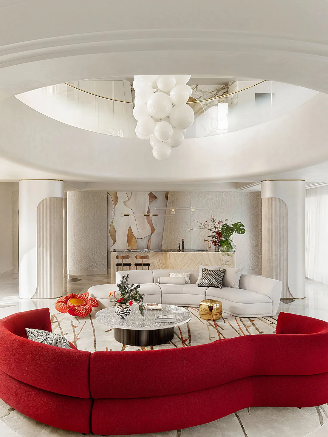 A modern living room featuring a red sofa and a white couch under a white ceiling with a unique light fixture.