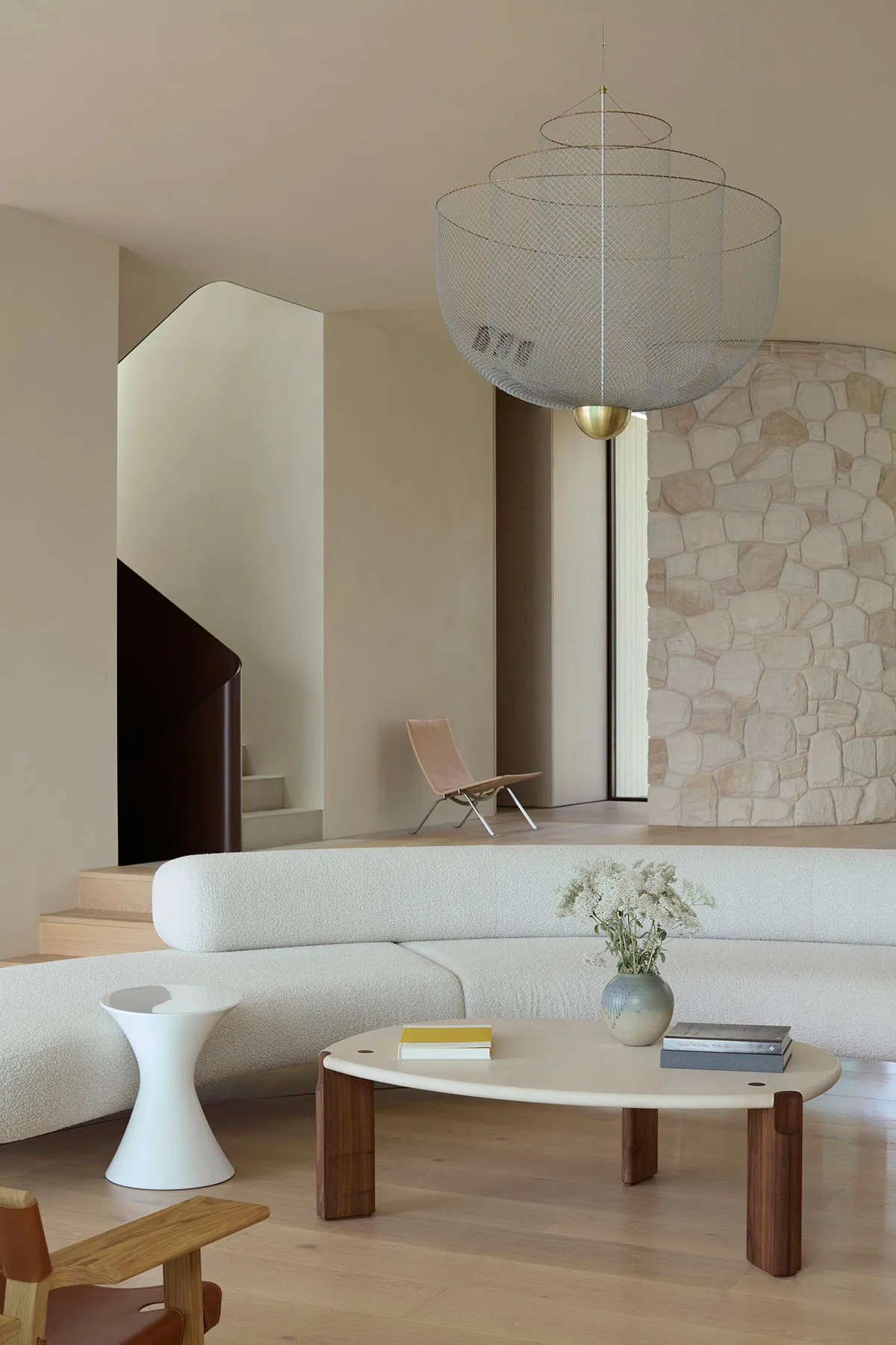 Modern living room featuring a curved sofa, coffee table, and wire chandelier hanging from the ceiling.