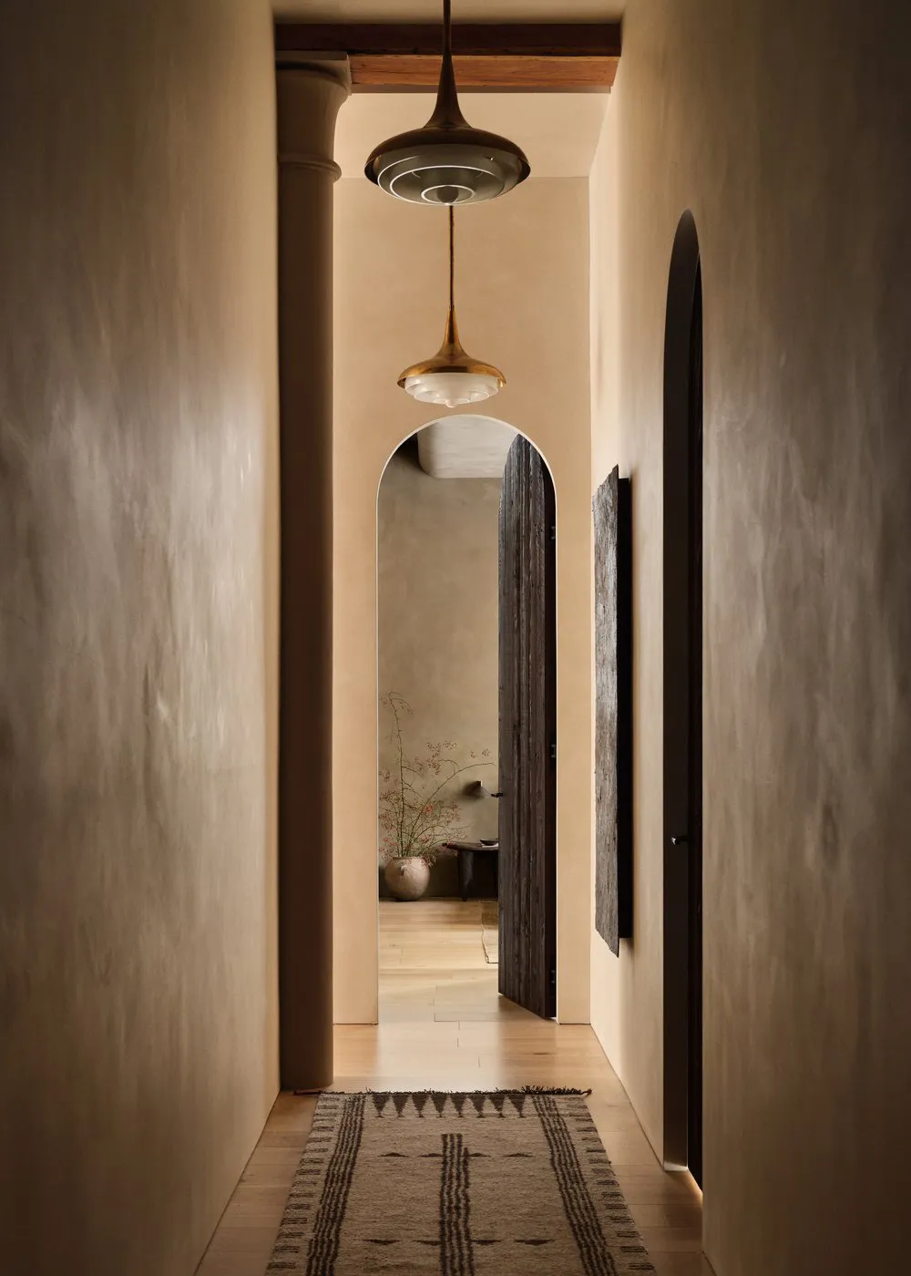 A minimalist hallway with concrete walls, wooden elements, and a rug.