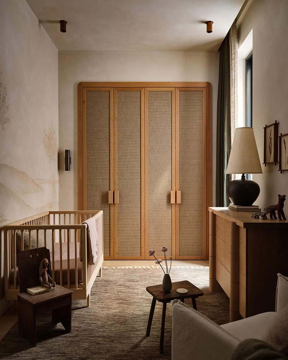A modern nursery with wooden furniture, a crib, a wardrobe, and various decorative items.