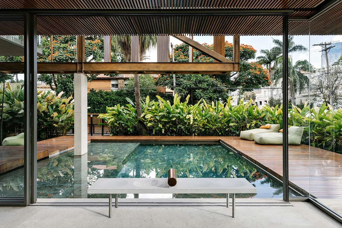 Modern residential pool with wooden deck and surrounding plants