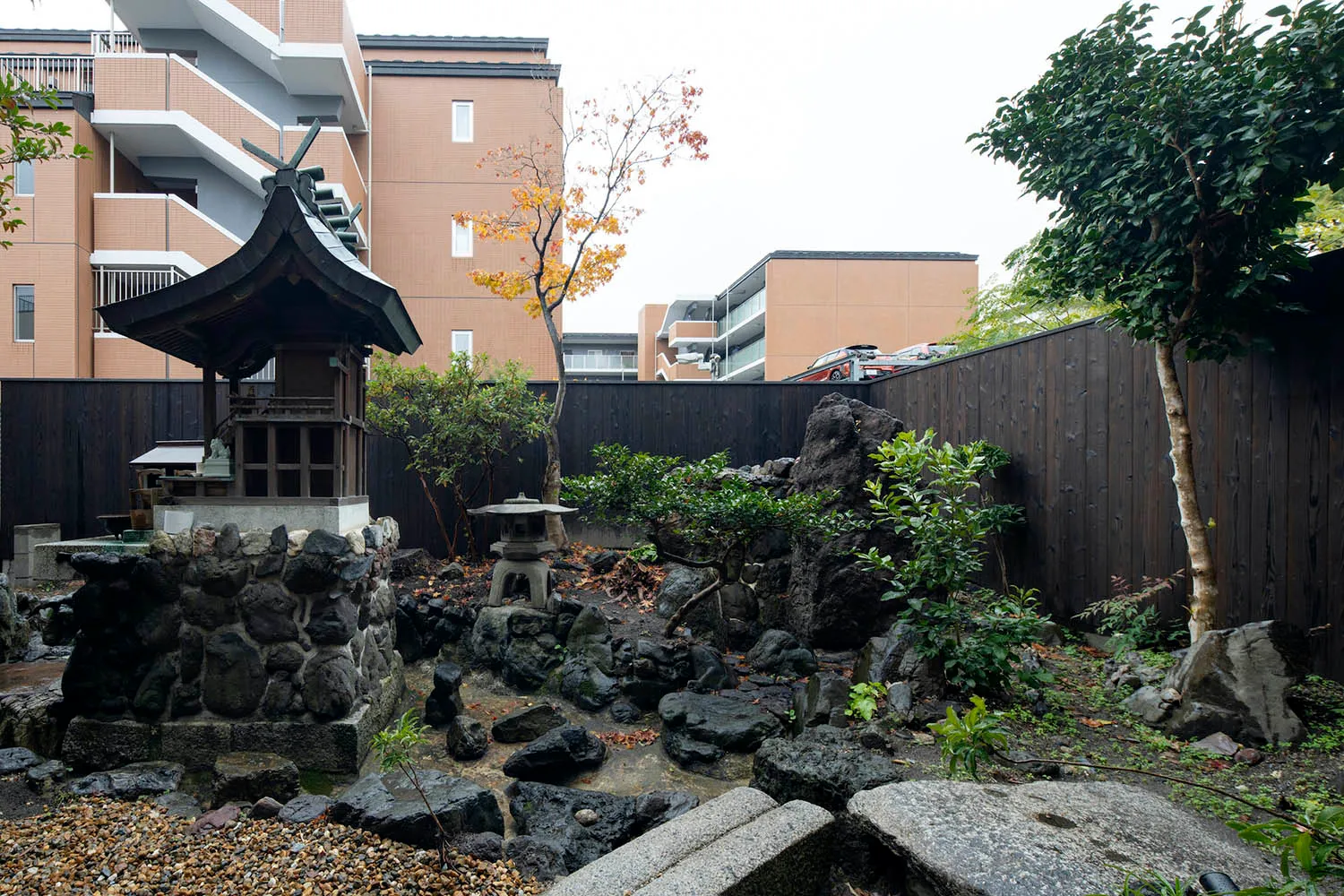 A serene Japanese garden featuring a stone monument, rock formations, and greenery.