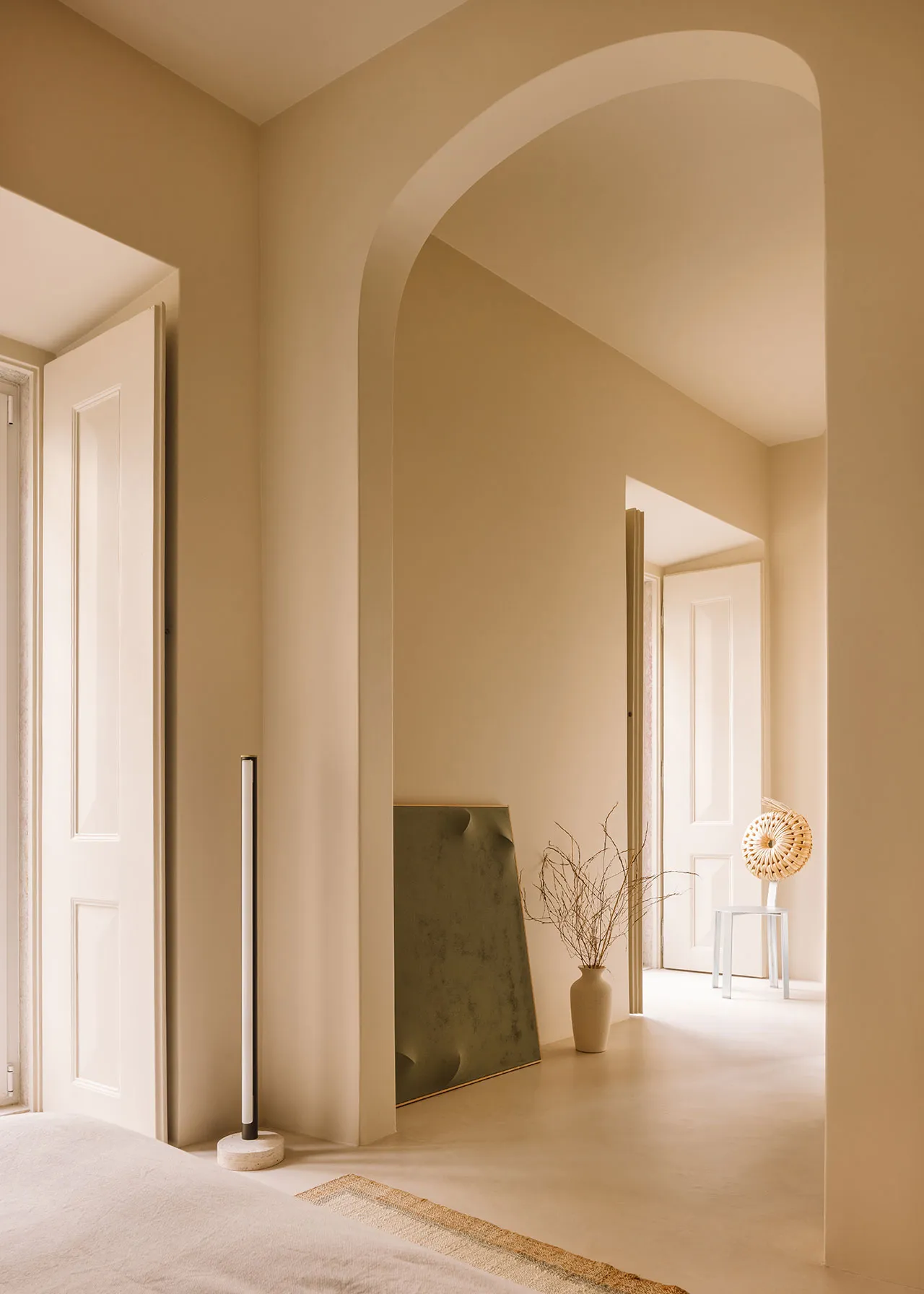 A serene minimalist bedroom featuring concrete walls, a natural rug, and minimal decor.