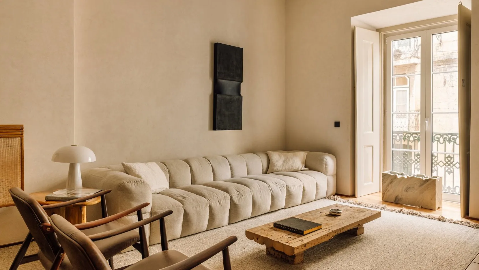 A minimalist living room featuring a fabric sofa, wooden coffee table, and marble accents.