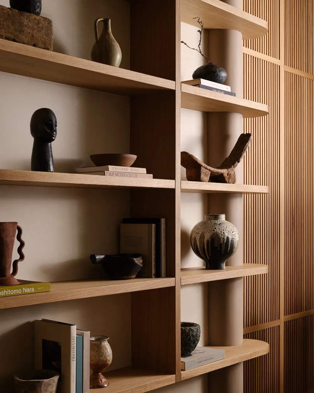 Modern interior design featuring a wooden shelving unit with various decorative items and books.