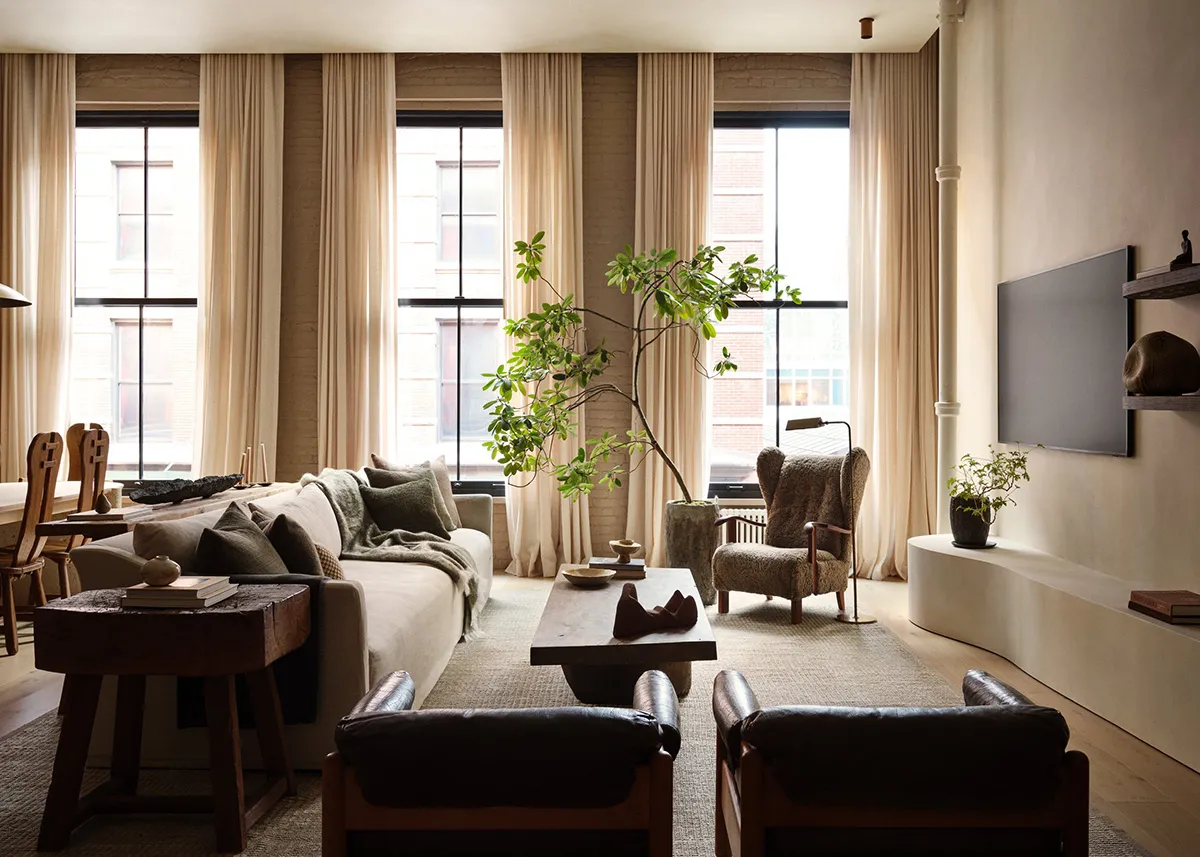A modern living room with a large sofa, armchairs, wooden tables, and a television on a low unit.