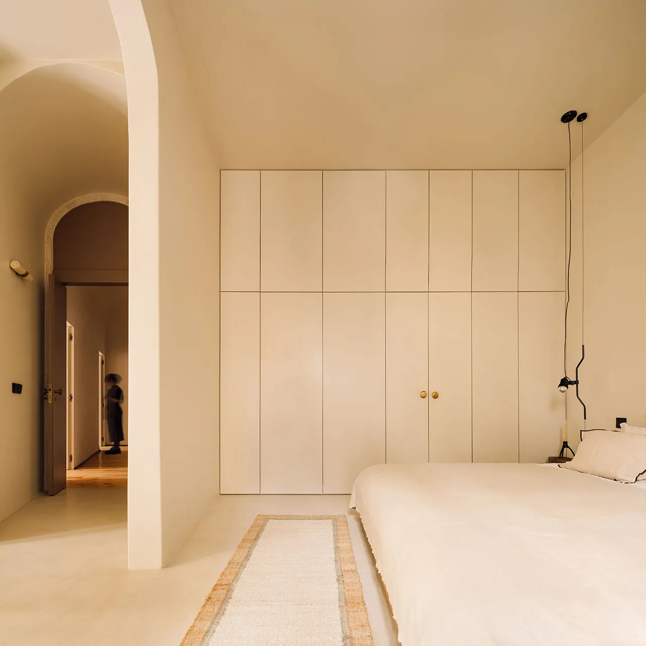 Modern minimalist bedroom with white wood flooring, cream color paneling on the wall, a single white bed with a headboard and