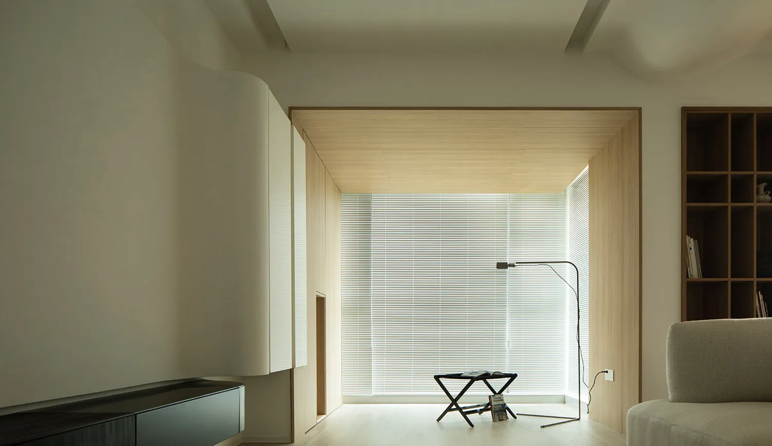 A minimalist living room featuring wooden walls, glass windows, and metal furniture.