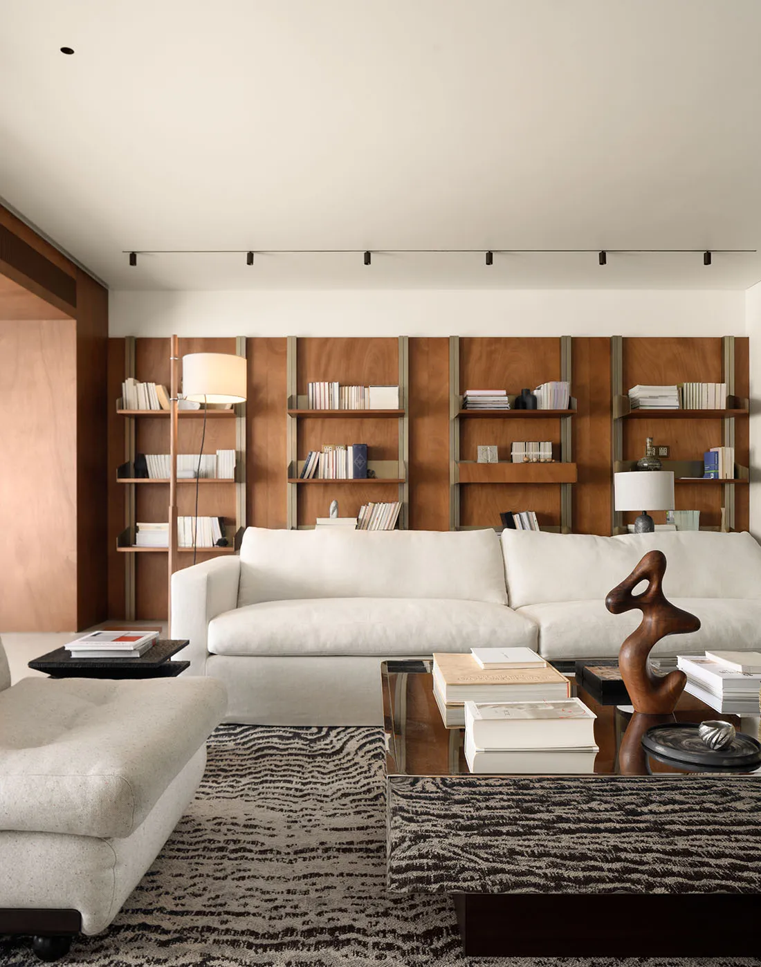 A modern living room featuring a white sofa, wooden shelves, and a floor lamp.
