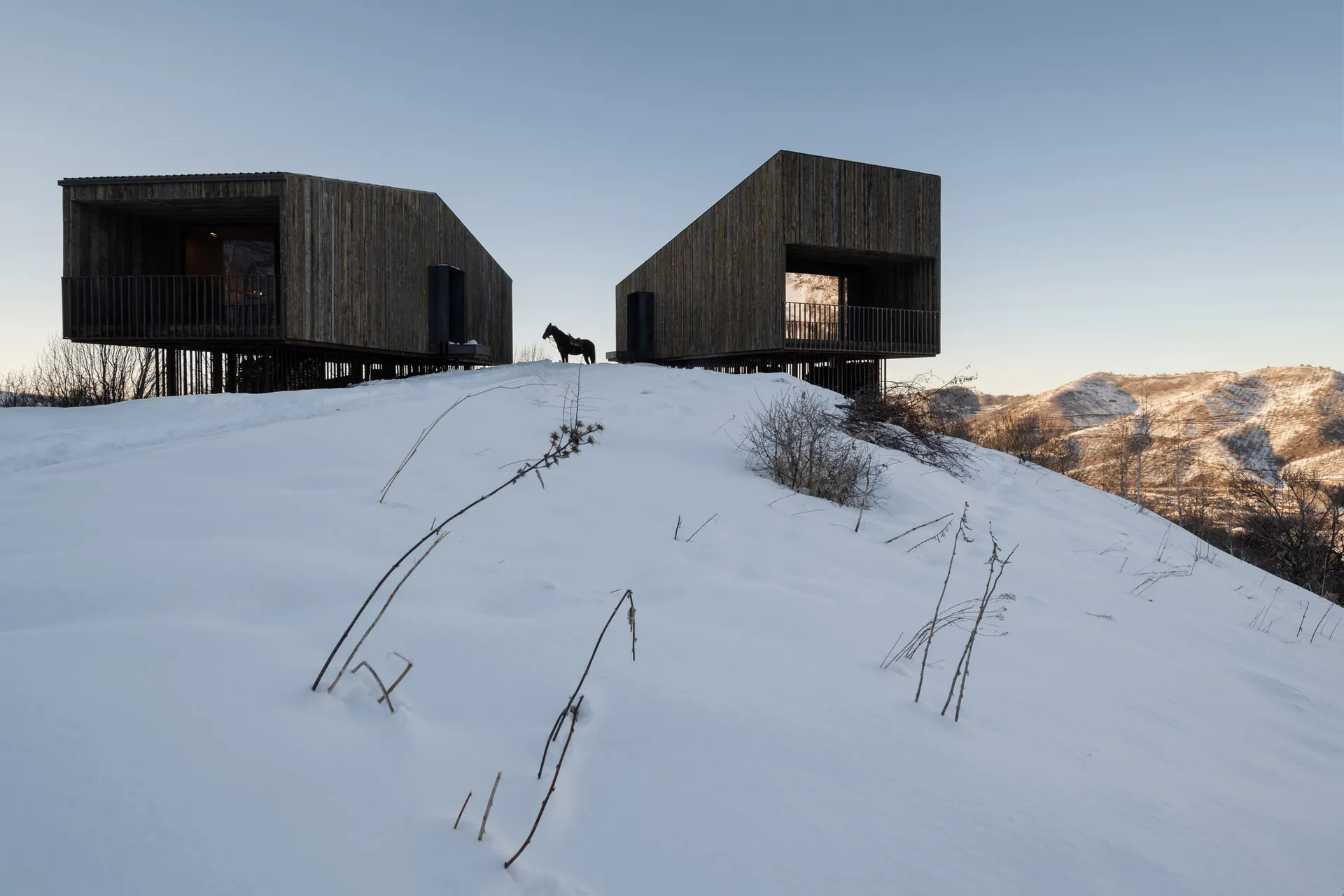 雪地山坡上的現代木質外牆住宅。