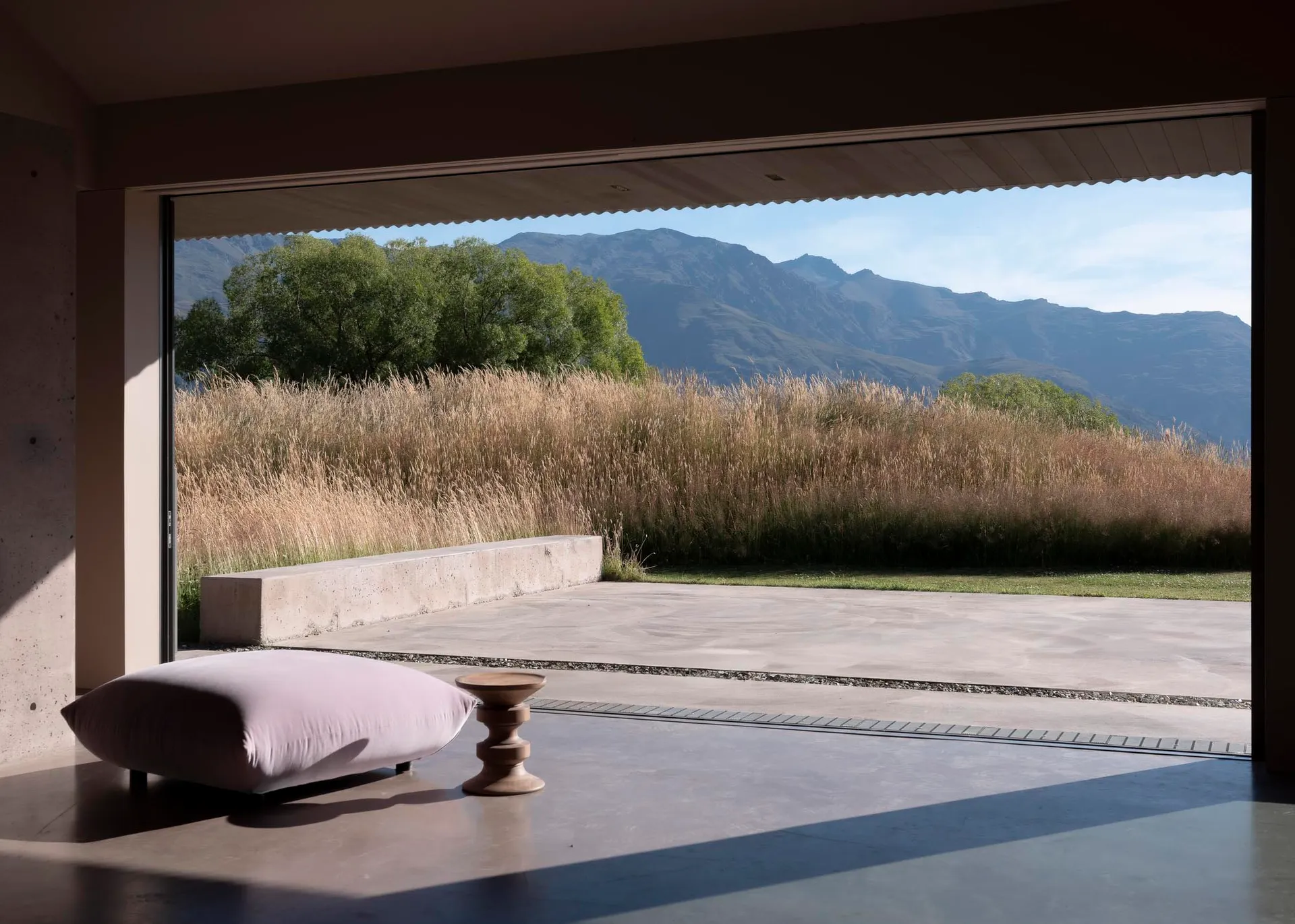 A minimalist residential exterior featuring concrete surfaces and grassy landscaping.